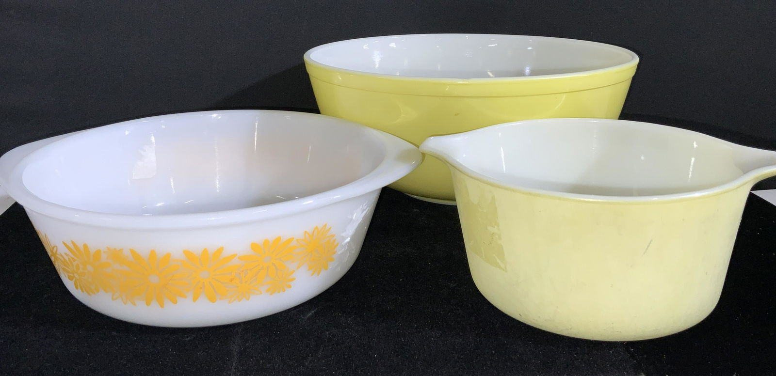 Lot 3 Yellow Trademark PYREX Ovenware Bowls: Three possibly vintage Pyrex bowls. All bowls are various yellow and white hues. Undersides read PYREX, OVENWARE, MADE IN USA. Largest bowl approx. 4.5H x 10W in. Medium sized bowl is handled and feat