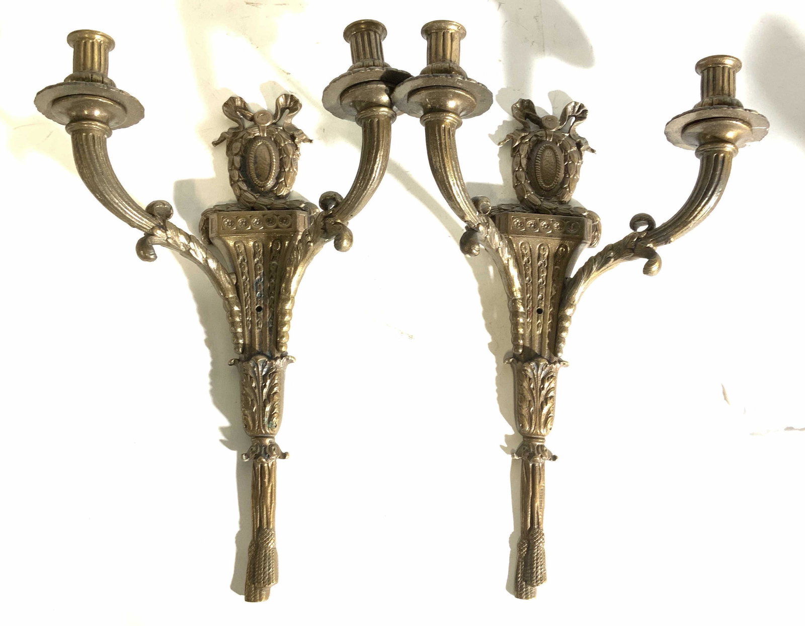 Pair Bronze Victorian Style Candle Sconces: Vintage Sconces with Laurel wreath and bow motif surrounding medallion, each sconce with two candleholders and embossed Laurel and lower tassel decor. 16.6 in ht, 11 in wide, 5 in depth from wall. Wei