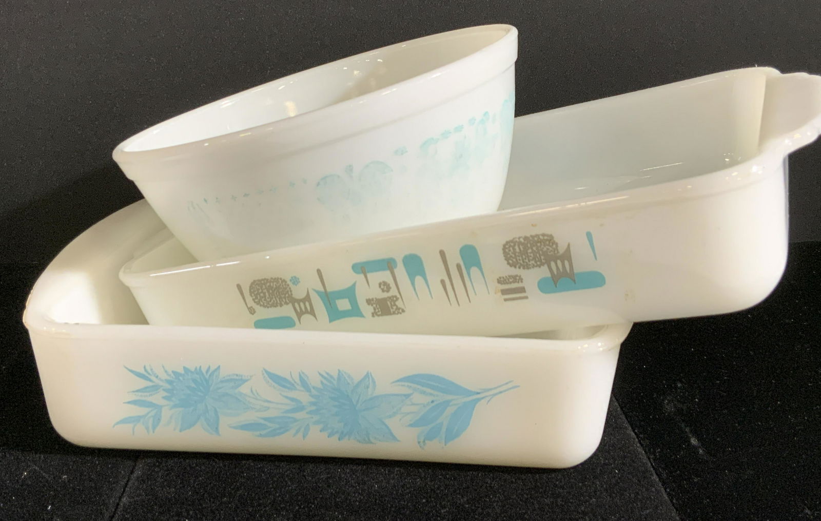 Lot 3 Signed Vntg Ovenware, Pyrex, Glasbake, More: Three vintage white ovenware baking dishes / bowls. Each piece features the blue hued patterns. Patterns feature florals, people, roosters, shapes, and more. Two pieces are handled. Undersides read PY