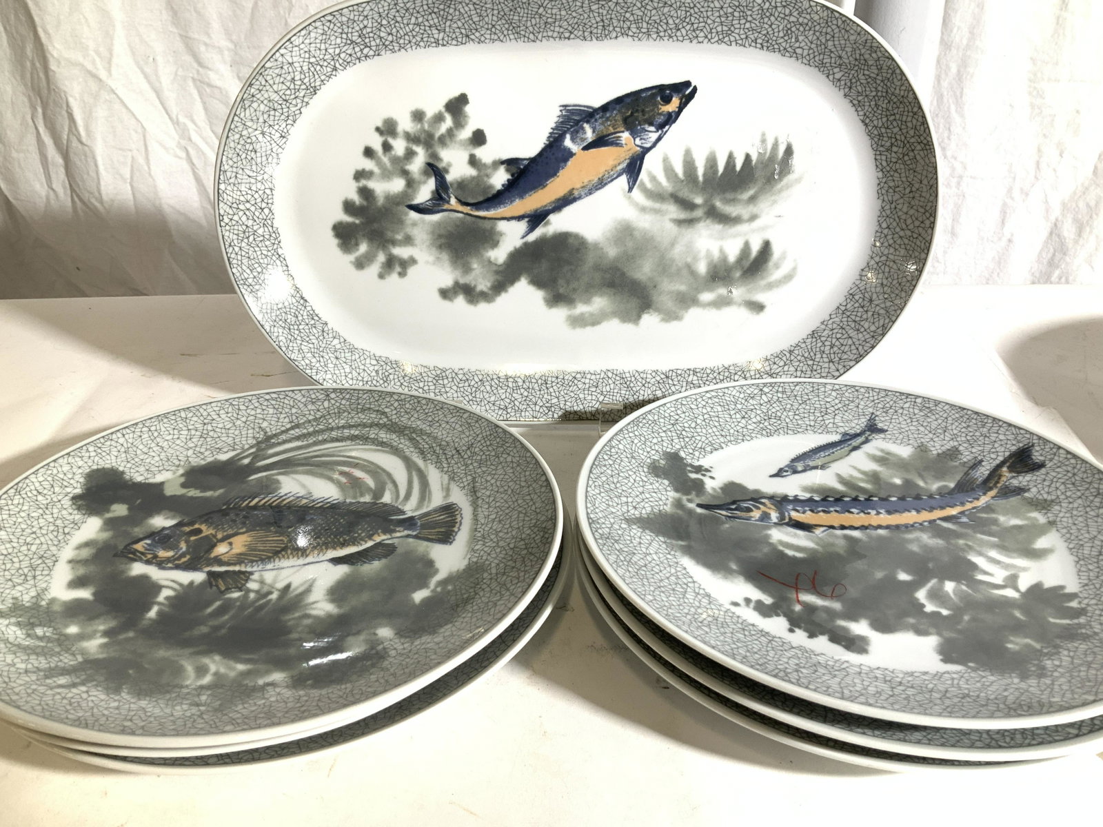 KAHLA Fish Motif Porcelain Dinnerware Set7: German Porcelain Plate Set with Fish Serving Platter and 6 dinner plates, all grey toned with image of different fish on each plate. Serving dish measures 14 5/8 x 8.75 in. All Hallmarked DISHWASHER S