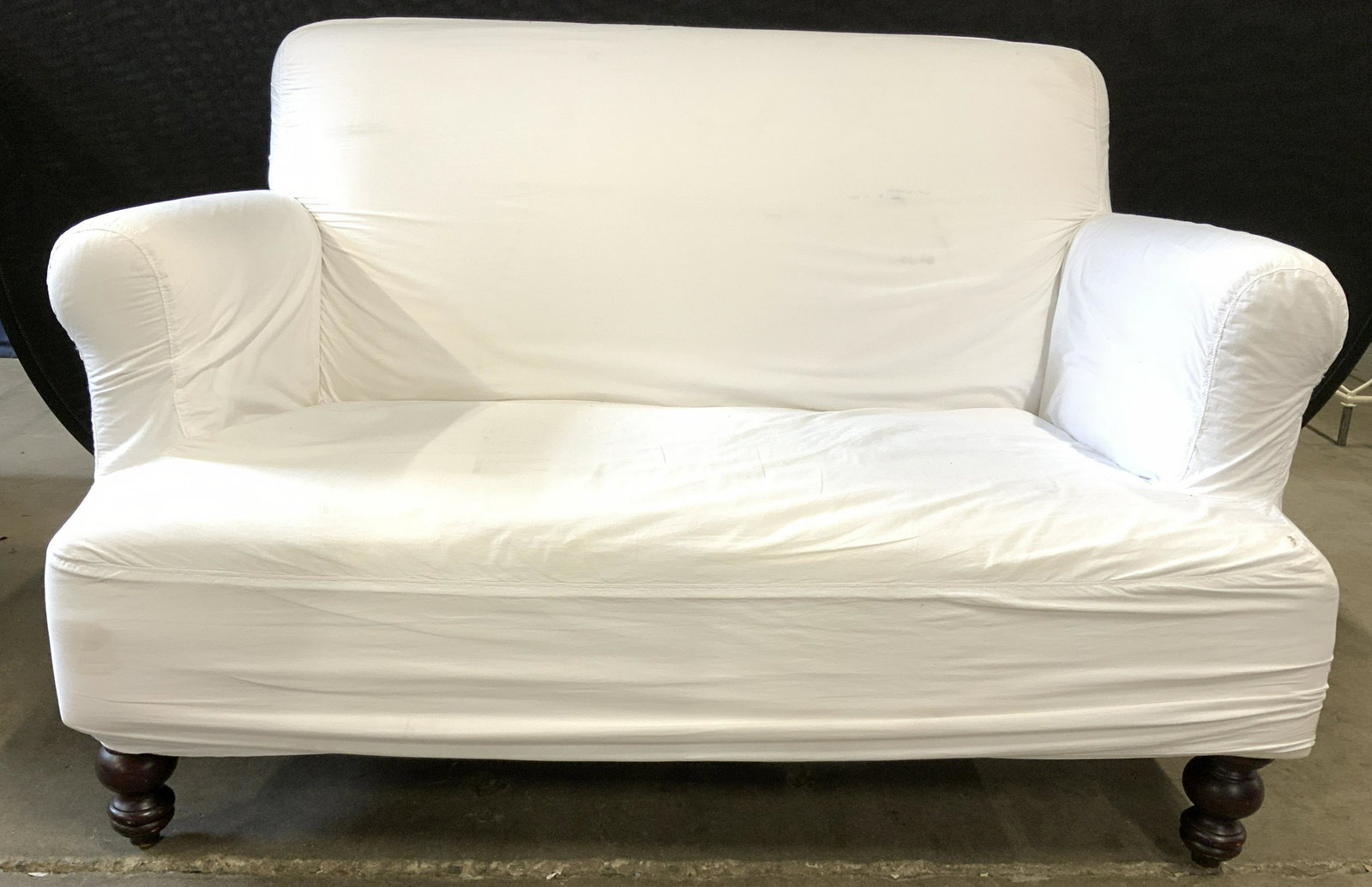 White Loveseat With Carved Wooden Legs: Loveseat is white toned. Piece has carved wooden legs which are possibly Mahogany. Piece measures approx 53 inches long 33 inches tall 36 inches deep. Loveseat, sofa, couch, white sofa, footed sofa. P