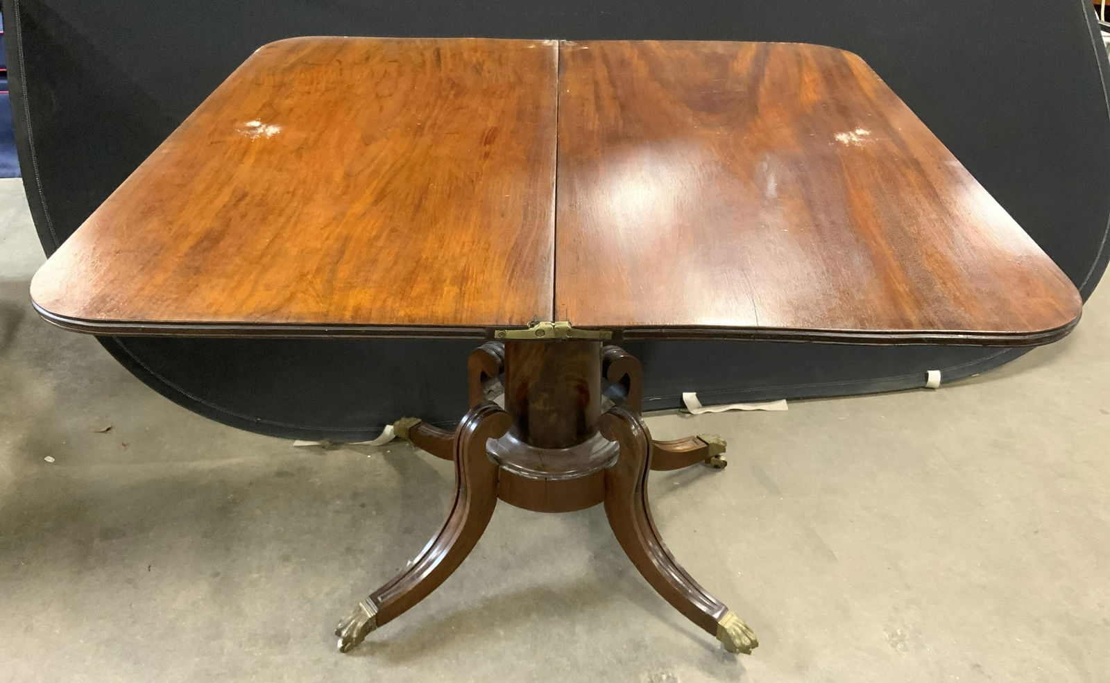 Vintage Flip Leaf Pedestal Table On Casters: Table is pedestaled. Piece is vintage possibly antique. Table sits on 4 gold toned brass casters. Flip leaf table, vintage flip leaf table, vintage furniture, pedestal table, table on casters. accent
