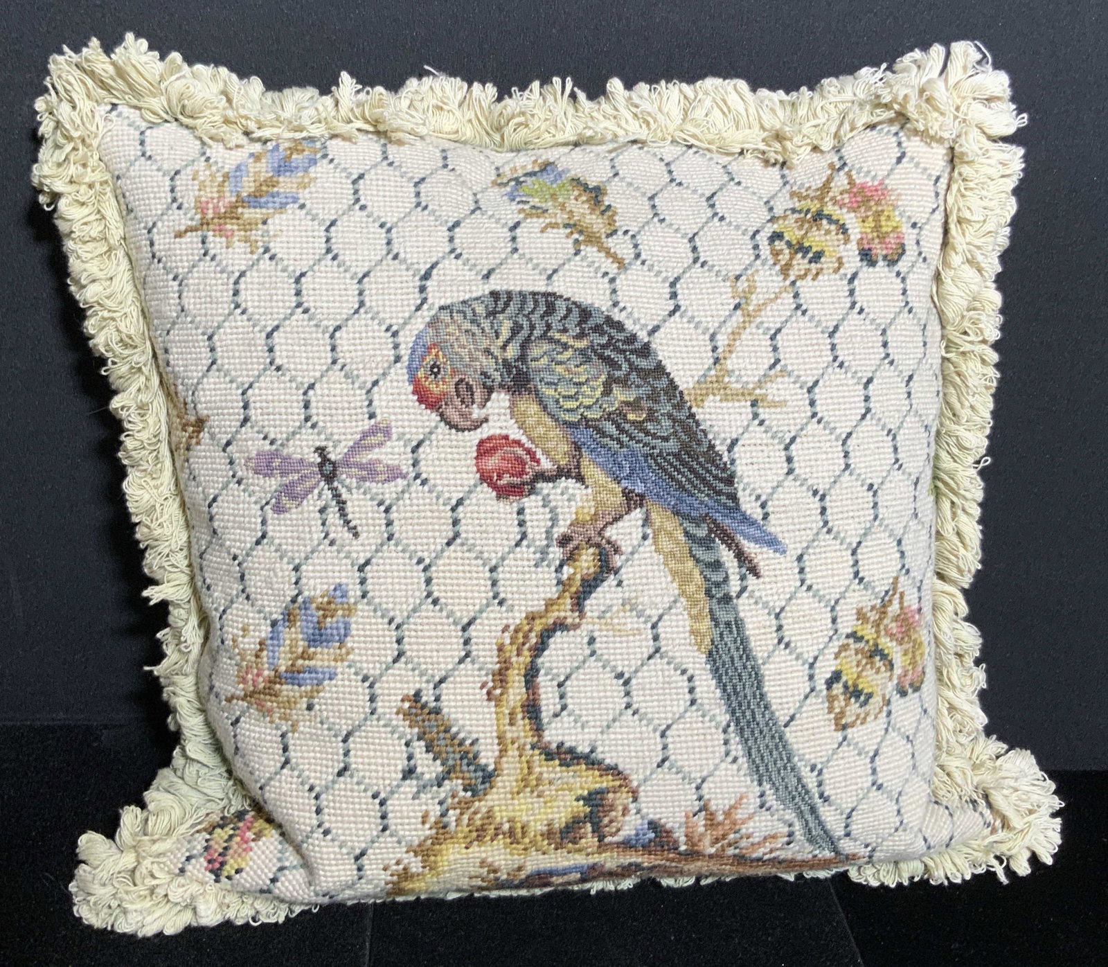 Vintage Handmade Needlepoint Parrot Motif Pillow: A vintage needlepoint point decorated with a parrot motif in the center. The parrot is depicted holding a piece of fruit and surround by insects and feathers. Underside is velour. Underside has a zipp
