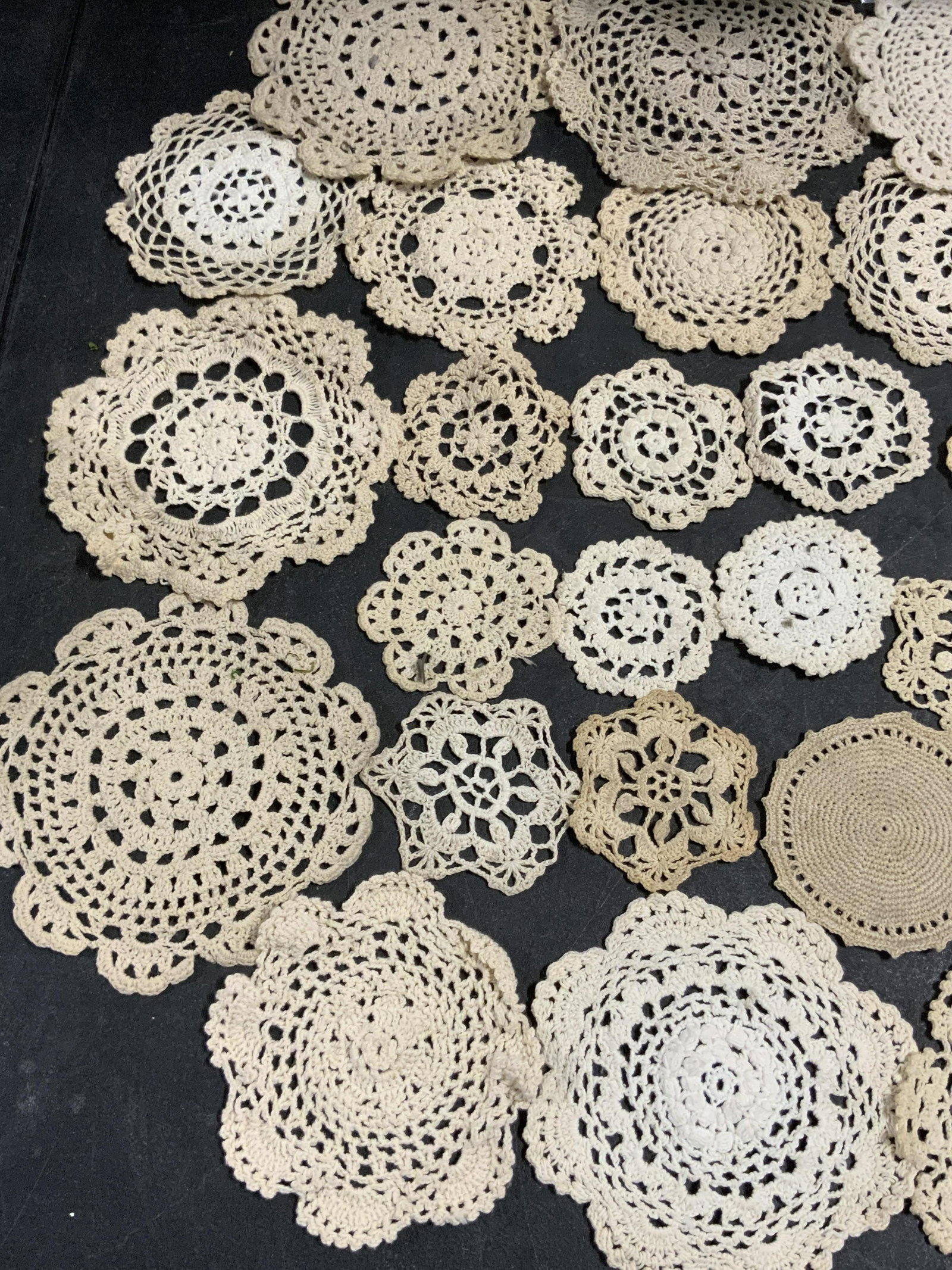 Lot 33 Vintage Handmade Doilies: A lot of 33 vintage handmade doilies. The pieces are primarily circular in shape, some have floral or snowflake shapes. Pieces are primarily beige hued. Varying sizes. Largest Approx. 8 x 8 in. Pieces