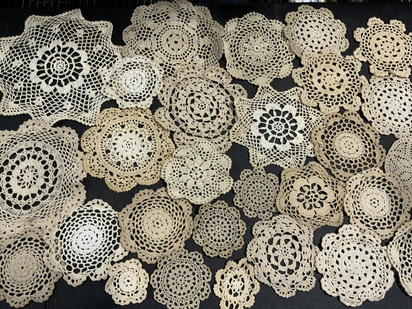 Lot 28 Vntg Handmade Doilies, Circle Forms & More: A lot of 28 vintage handmade doilies. The pieces are circular, snowflake, and star forms. Pieces are primarily beige hued. Varying sizes. Largest Approx. 11 x 11 in. Pieces have some wear, some discol