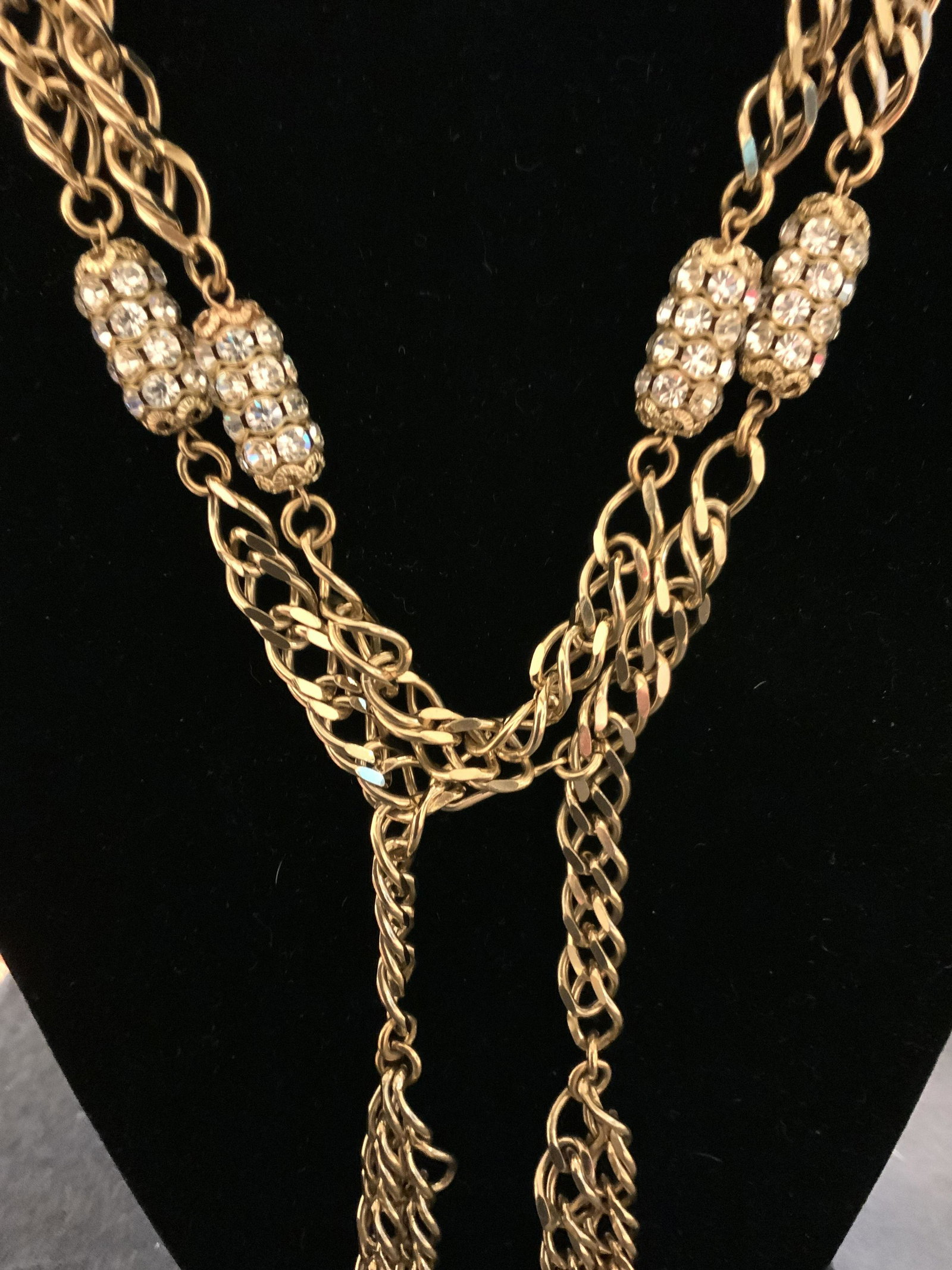 Chunky Gold And Crystal Tassel Necklace: Vintage costume jewelry, long chunky gold toned chain with elongated gold capsule style design with inset rhinestones crystals, piece has weight, drop has interlocking tassels of same design, tassels 
