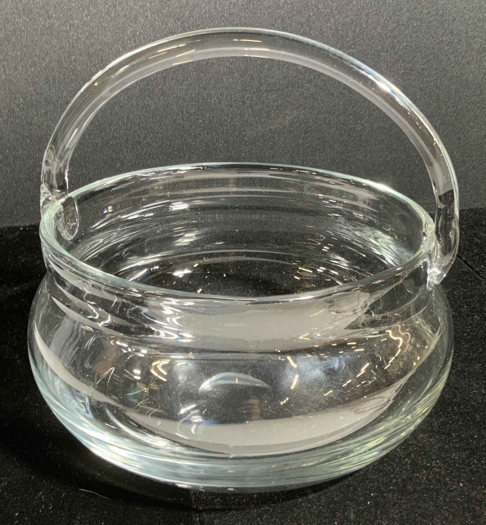 Art Glass Basket Form Vessel: An art glass vessel crafted into the form of a basket. The piece is crafted from colorless glass. Can be used as a decorative tabletop display, for storing candy or trinkets, and more. Piece has some 