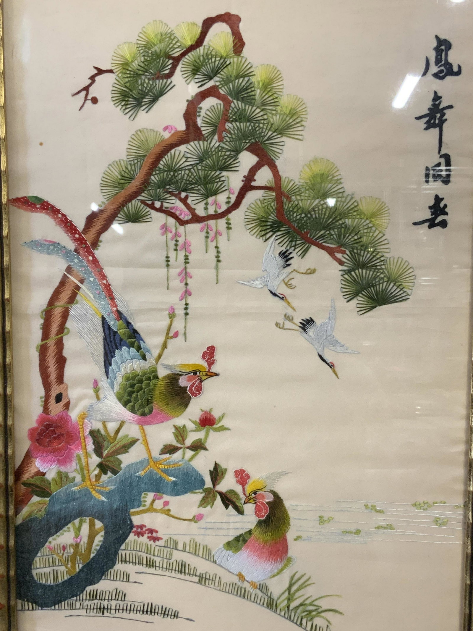 Framed Chinese Embroidery Artwork: Framed Chinese Embroidery, Chinese text to the upper right corner, subject birds on a hillside embroidered on a tan background, gilt wood frame, measures 20 inches tall by 13 inches wide, not examined