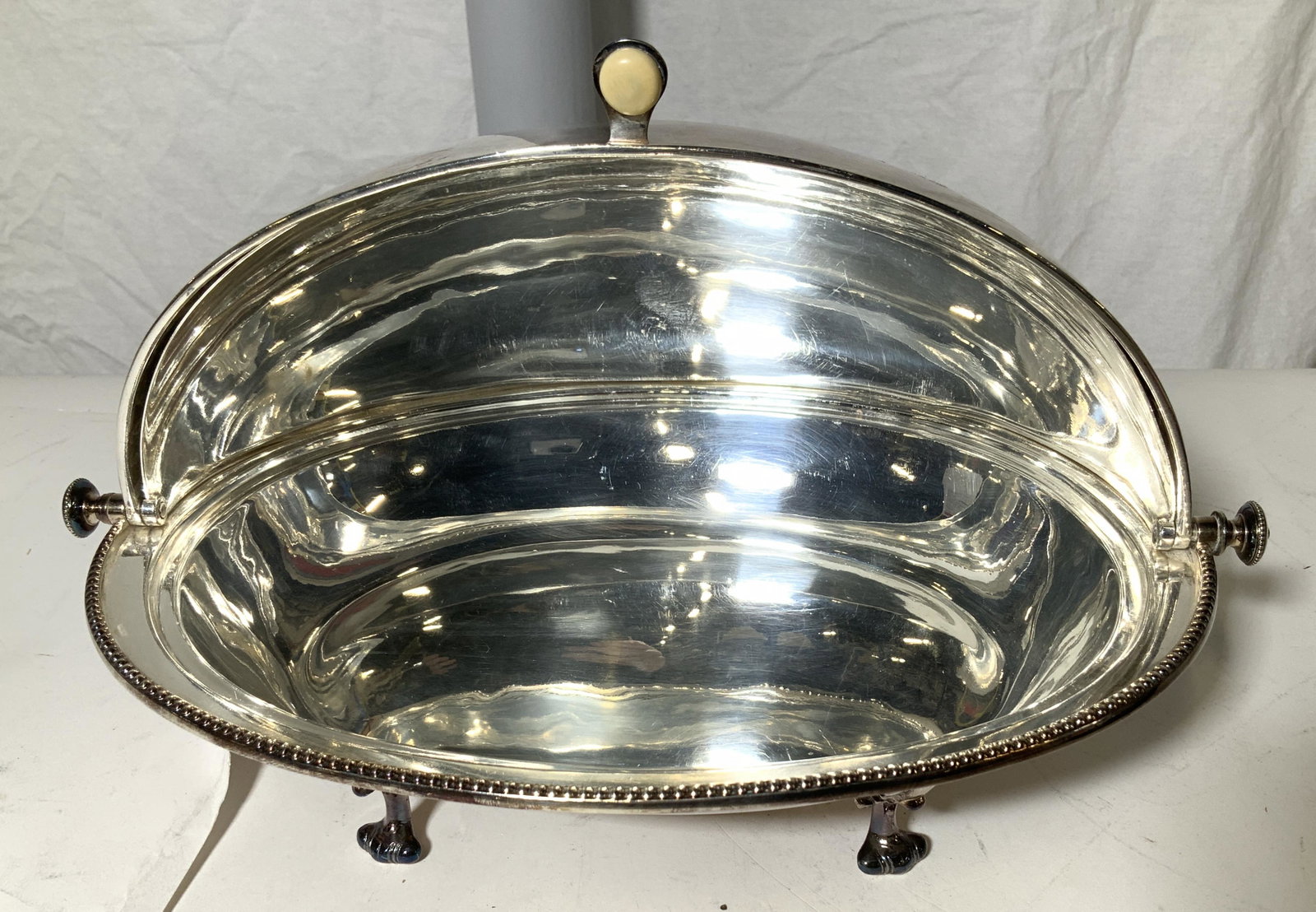 Fine Silver Plate Chafing Server, Antique: A swivel dome top server decorated with a dotted rim, Bakelite / or synthetic bone button Lift knob and raised on Laurel decor scroll feet. With a separate pierced warming plate and solid drip plate i
