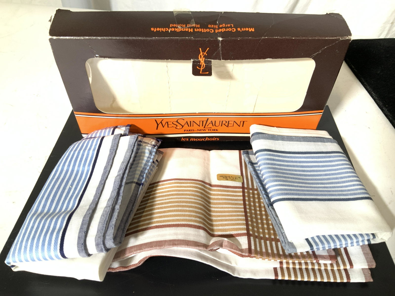 Never Used Box of 3 YSL MEN’s Cotton Handkerchiefs: Yves Saint Laurent Paris New York Hankies- Two unused handkerchiefs, one possibly unused. All Hand rolled ( sticker on one), white white with stripes, either blue or Brown- beige stripes. Comes in a Y