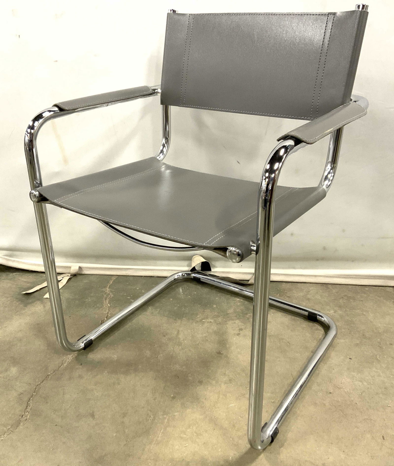 Grey Leather Cantilever Chair: Grey leather cantilever chair. Polished chrome tubular frame. Underside of seat supported by curved bars. Wear is consistent with age and use. Measures approx 31.5 inches H, 23 inches w, and 21 inches