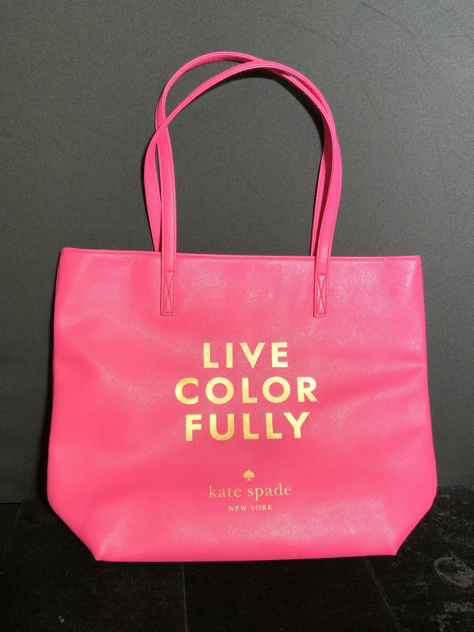 KATE SPADE NEW YORK Hot Pink Tote Bag: Never used ladies tote bag. A vibrant, hot pink tote bag that reads LIVE COLORFULLY, KATE SPADE, NEW YORK. The interior of the bag is orange hued and possesses a pocket. Approx. 14L x 17W in. Strap dr