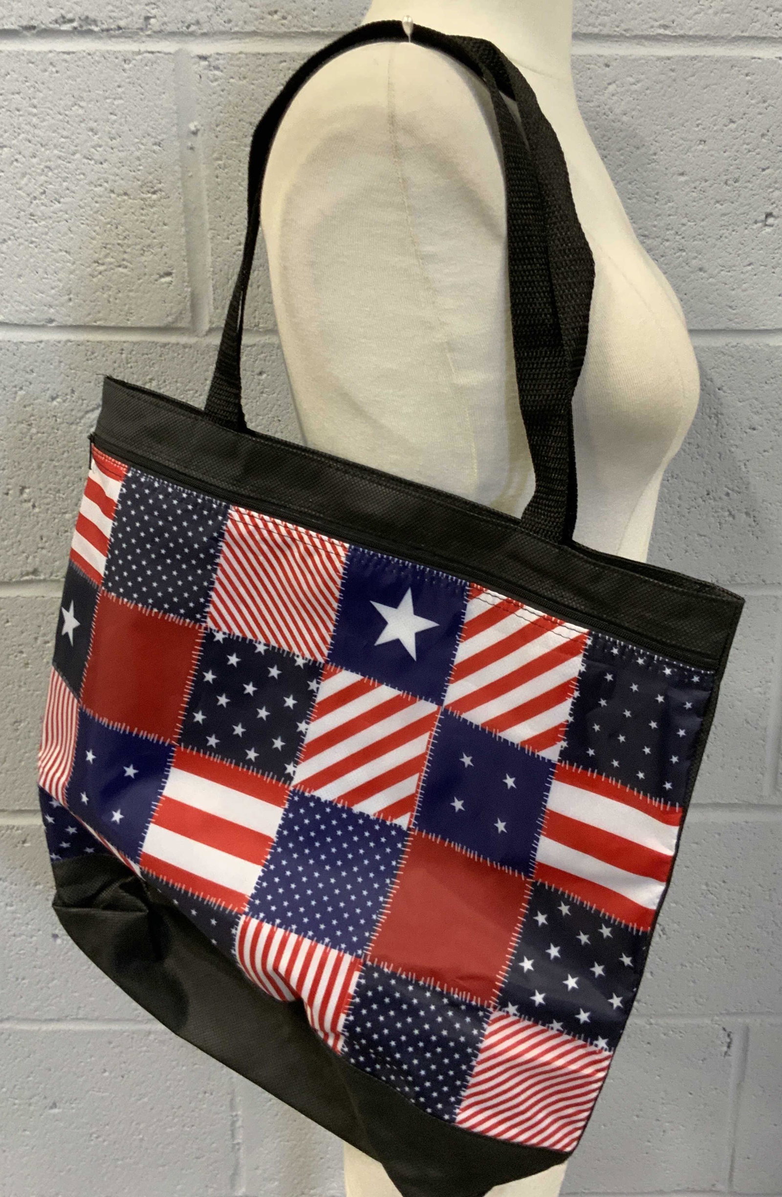 Stars & Stripes Flag Style Shoulder Bag: Never used tote bag decorated with flag style designs. Primarily black with blue, red, and white hued accents. Stars and Stripes throughout the obverse. Velcro and zipper closures. Approx. 16L x 16W i