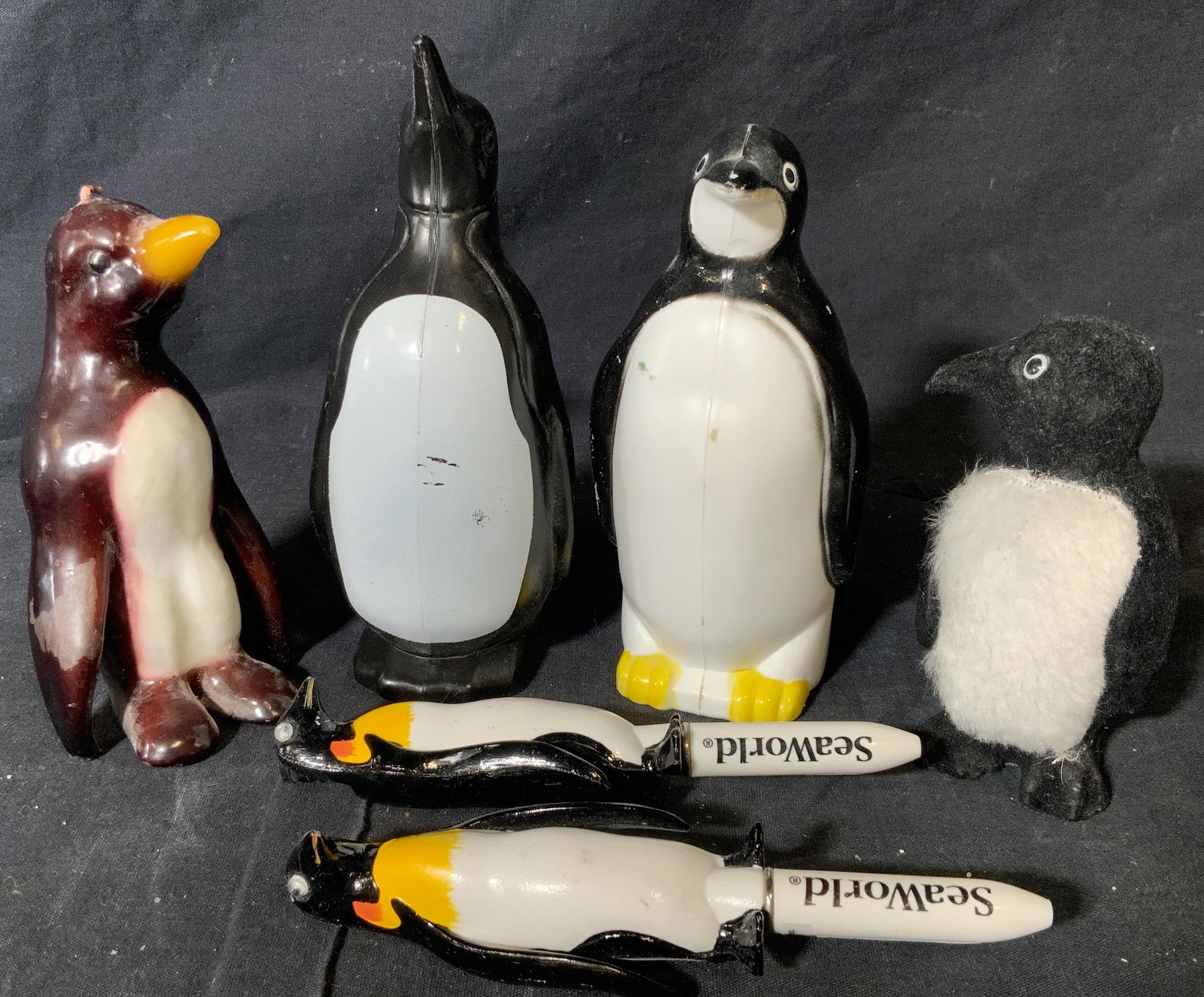 Group Lot 6 Penguin Paraphernalia Firgurals: Group lot 6 penguin paraphernalia figurals, lot consists of two SeaWorld penguin pens, two composite penguin figurals, one felt penguin figural, and a burgundy penguin candle, tallest of the group mea