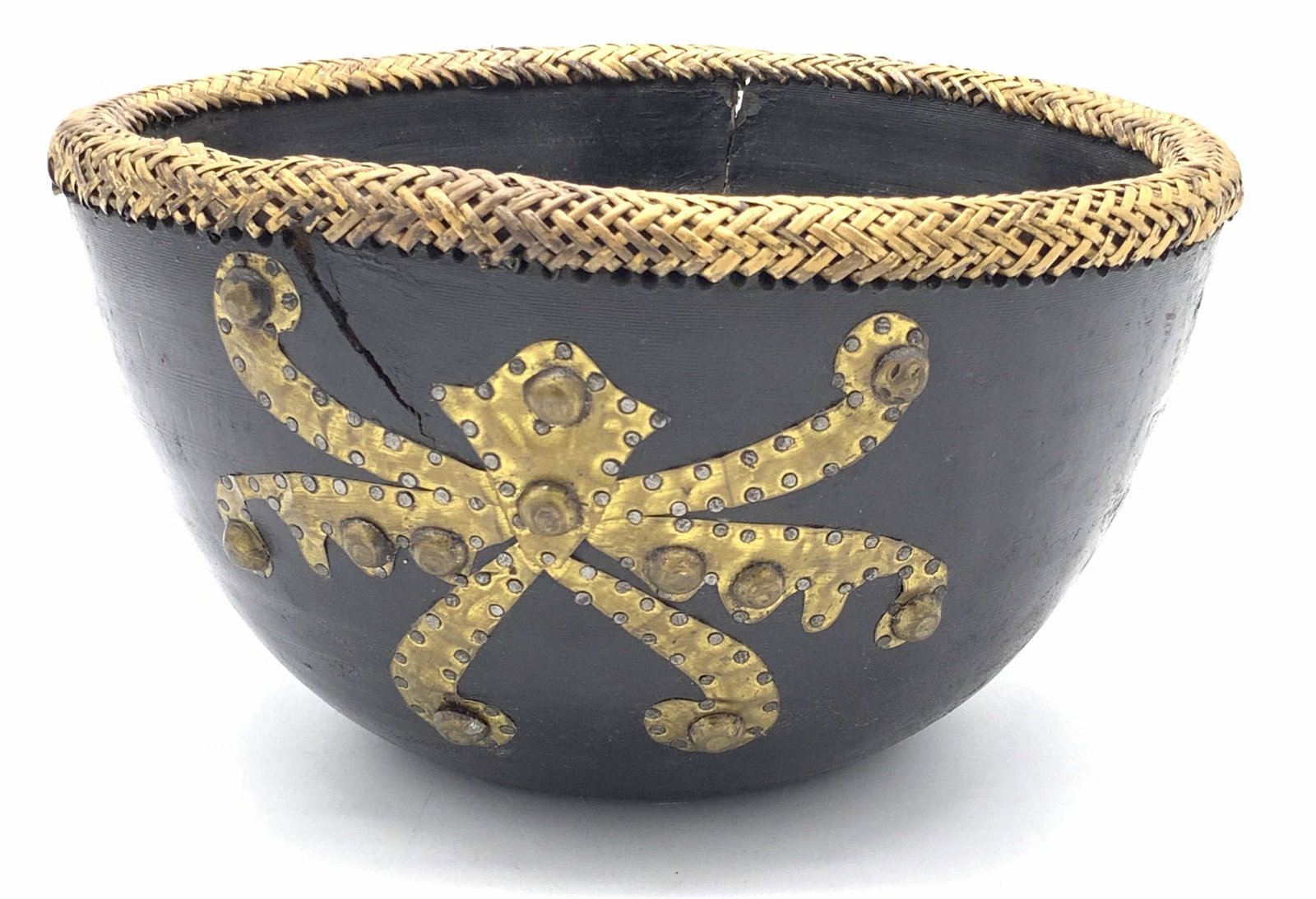 Handmade Indonesian Wooden & Straw Rimmed Bowl: A handmade and painted wooden bowl with a woven straw rim. The sides are decorated with metal, possibly brass, studded, hammered, and inlaid accents. Underside sticker reads MADE IN INDONESIA. Approx.