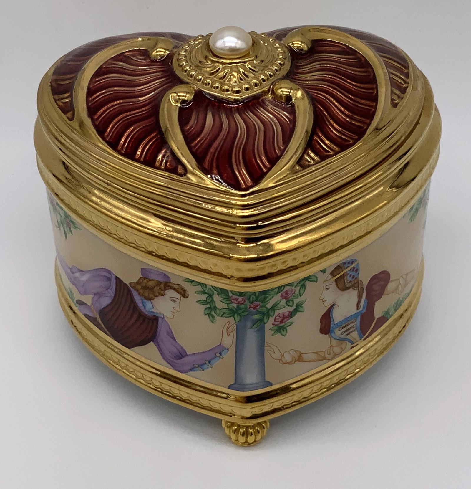Porcelain Trinket Music Box: Porcelain trinket music box, text to underside reads ‘Romeo and Juliet TFM’ and ‘Crafter in Taiwan’, box in a heart shape with a pictorial scene to the sides of Romeo and Juliet reaching for o