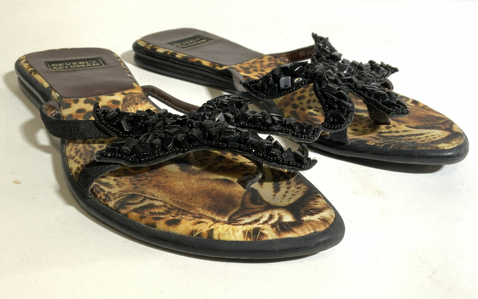 Pair BEVERLY FELDMAN Leopard Sandals Size 8M: Each sandal is marked BEVERLY FELDMAN. Sandal soles have leopard faces. Each have black toned shoe ornament. Undersides read “I love Beverly Feldman I really do too much is not enough”. Beverly Fe