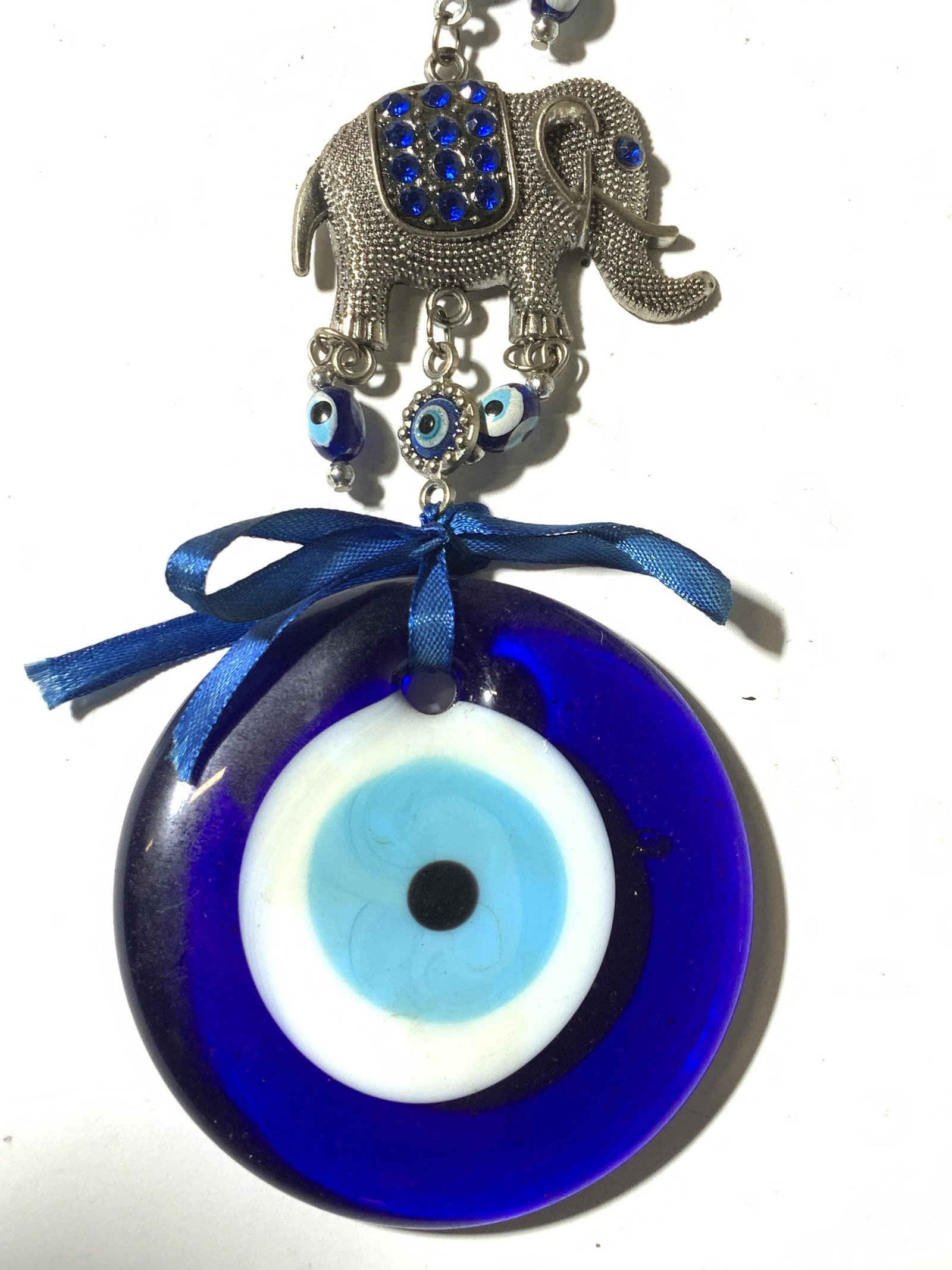 Elephant & Evil Eye Home Decor Ornament: Mixed Textiles Elephant Hanging Home Decor Ornament with 3 metal elephants adorned with blue rhinestone eyes and covers, drips g with protective evil eye culminating in large art glass eye. Clasp for 