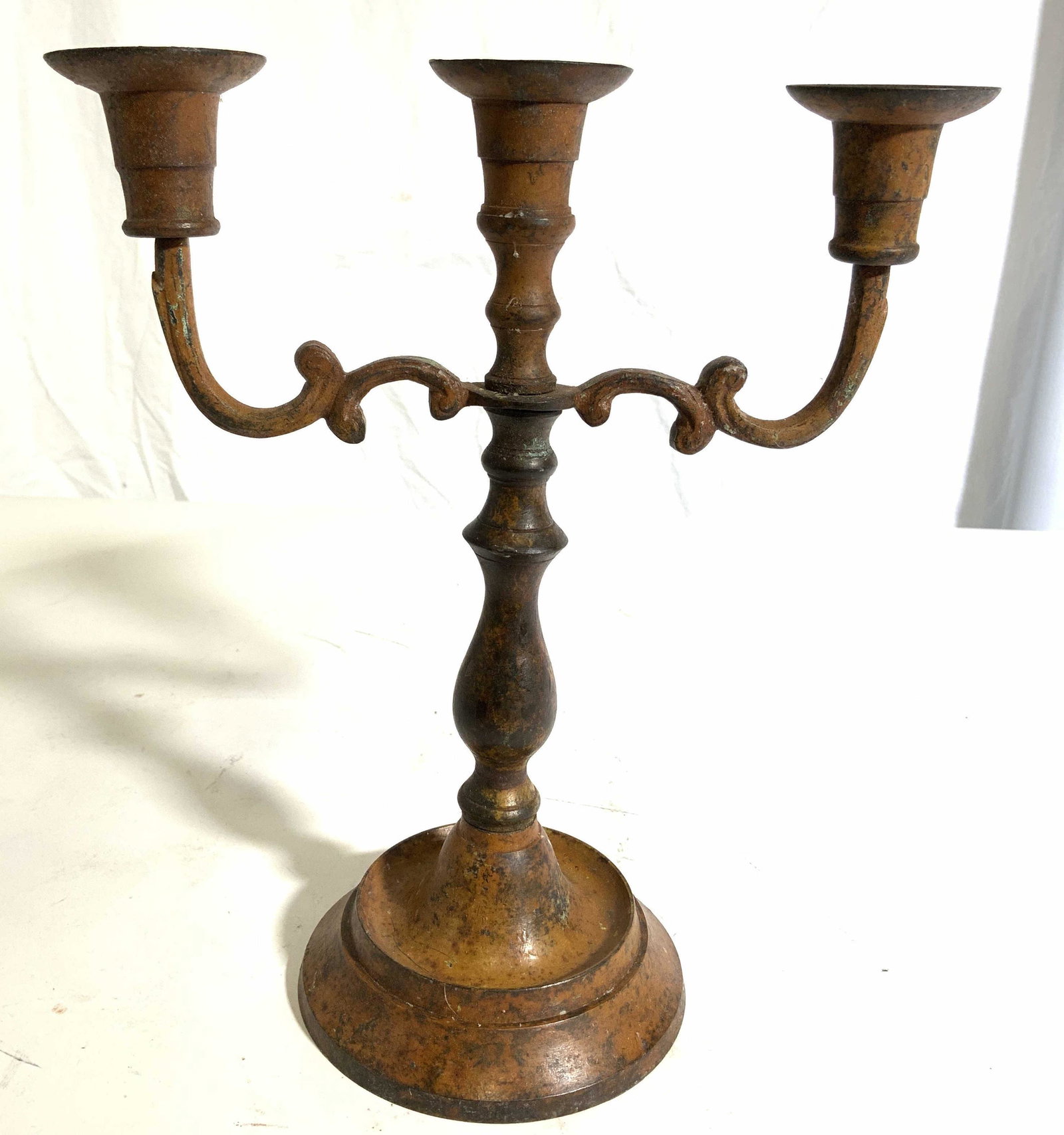 Vintage Metal 3 Arm Candelabra: Candelabra is vintage. Piece is metal with rustic appearance. Candelabra has 3 arms. Base is circular shaped. Arms have c curve shaped structures. Piece measures approx 10 inches tall 9 inches wide 4.