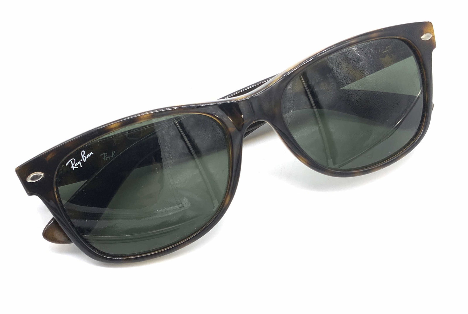 RAY BAN Signed Ladies Italian Sunglasses: A pair of tortoiseshell style sunglasses. Primarily black with brown hues. Interior is signed RAY BAN, MADE IN ITALY. Obverse reads RAY BAN as well. Approx. 2L x 5.5W in. Piece possesses some wear con