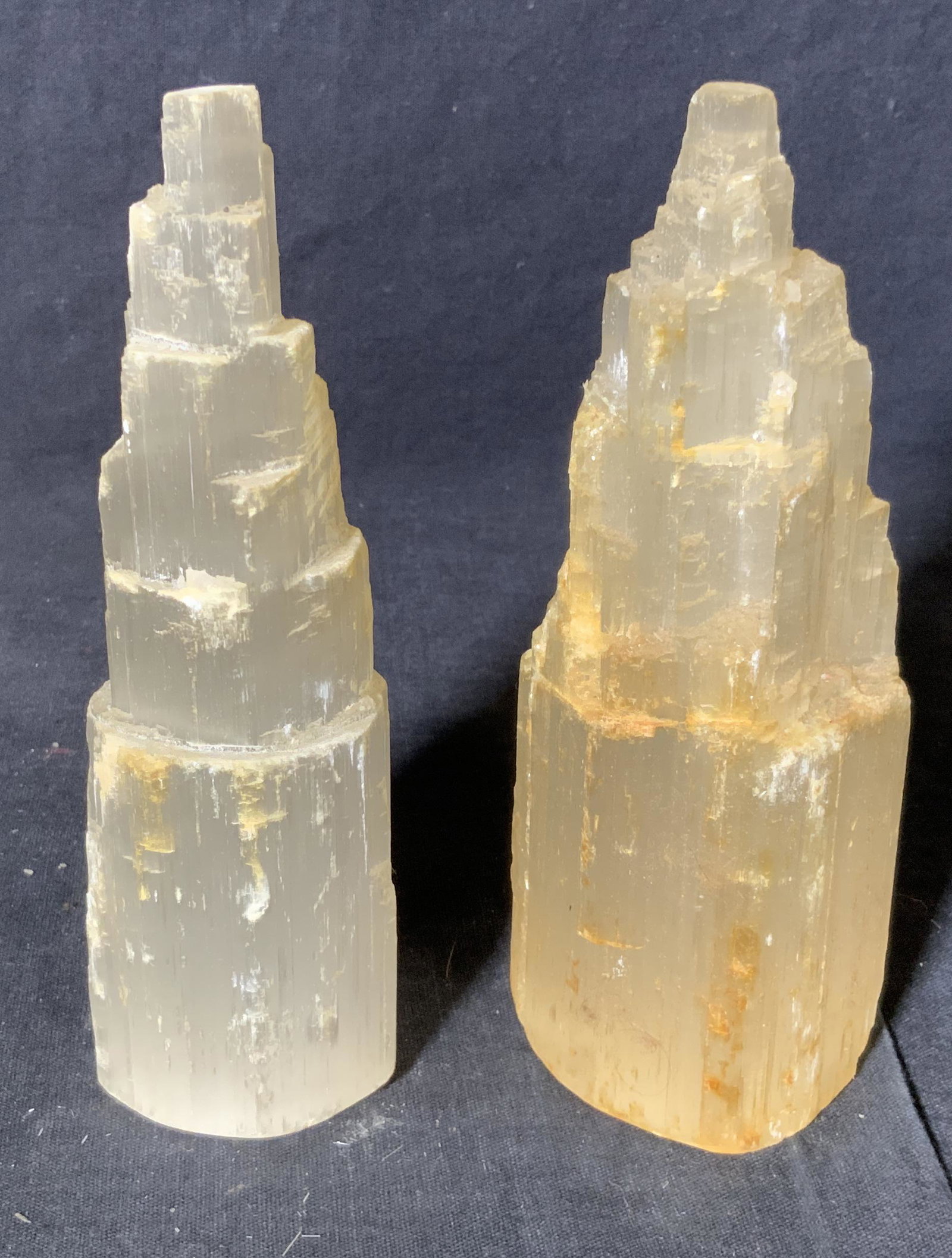Pair Selenite Prismatic Towers: Pair Selenite Prismatic Towers, both are in a cylindrical prismatic tower formation, one has more of a yellow tint to it than the other, larger of the two measures 6 inches at tallest point, some wear