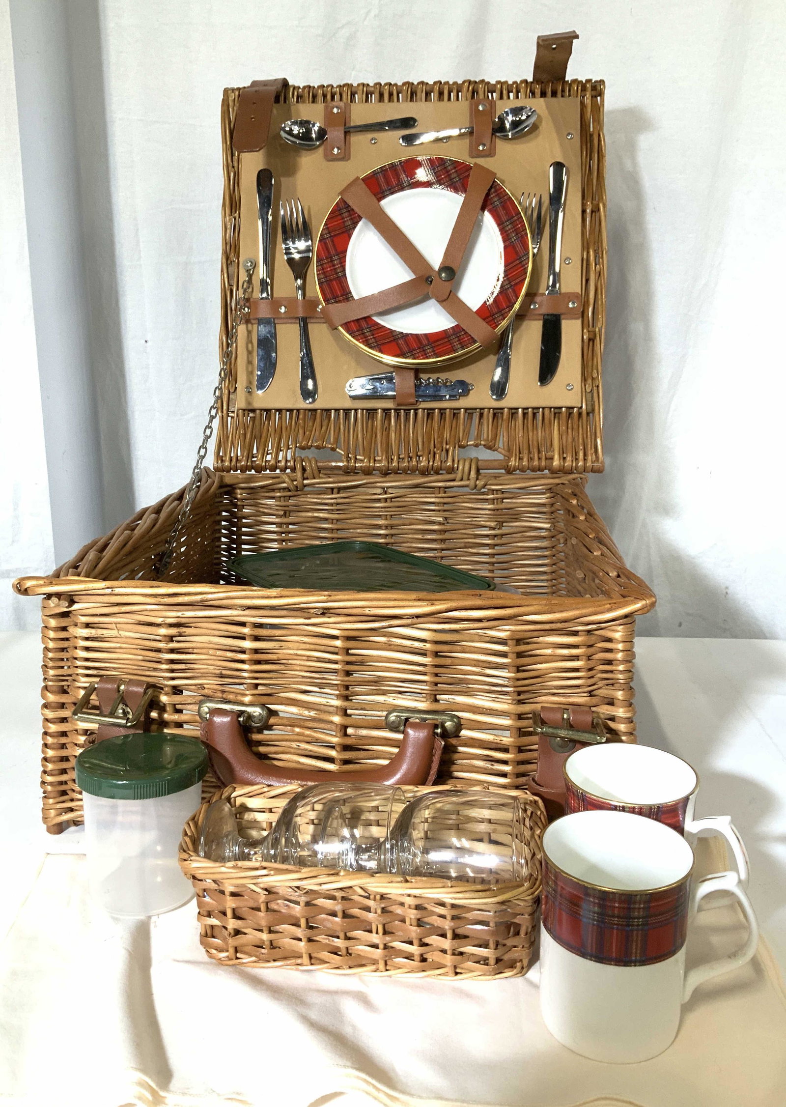 Country Wicker Picnic Basket w Cutlery, England: Top Loading wicker Picnic basket with 2 belted Closure and strong carry handle. Attached to underside of lid are Checkerboard pattern porcelain plates, marked Royal Crown Duchy Fine Bone China England