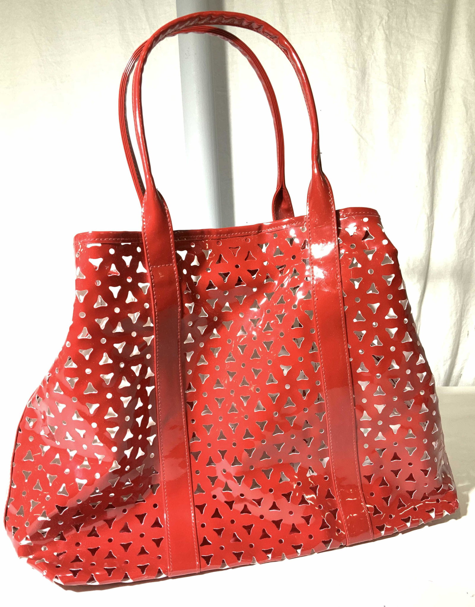 Este Lauder Red Pierced Faux Leather Tote: A red faux patent leather carry all tote, labeled ESTE LAUDER on inner label , snap closure, makes a great beach bag, pierced material. 17.5 x 11 in. Opens wide. Fits a lot. Appears seldom used. Ladie