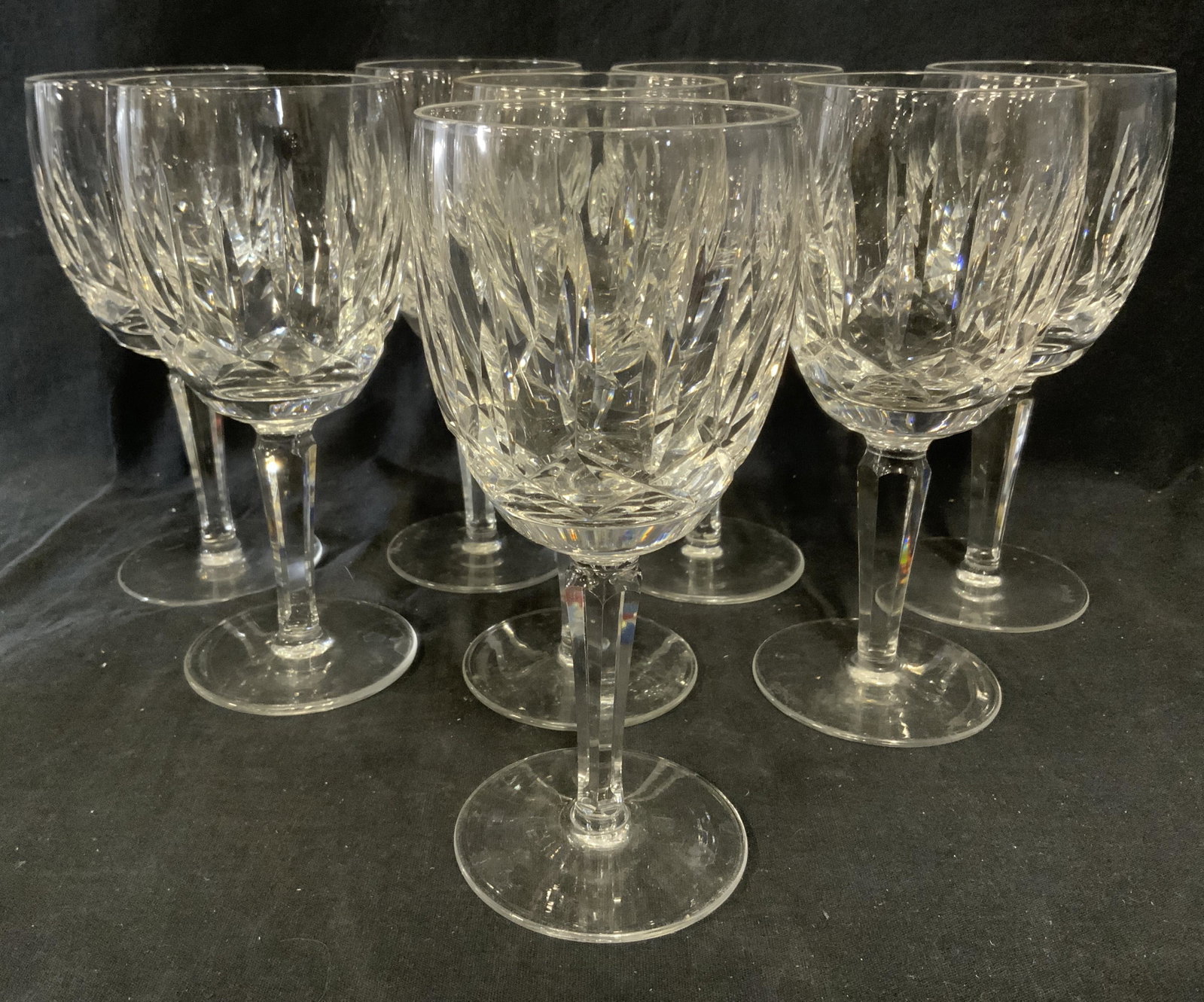Set 8 WATERFORD Cut Crystal Stemware: Set of 8 cut crystal stemware glasses. 7 in by 3 in. Underside of glasses each read as WATERFORD. Wedge shaped carvings decorate glass. Wear is consistent with age and use. Stemware, wine glasses, cut
