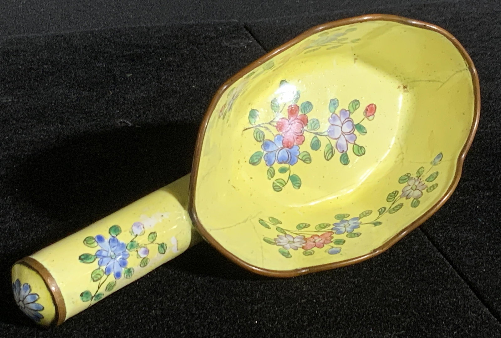 Floral Motif Chinese Porcelain Silk Iron: A glazed yellow hued porcelain & metal rimmed Chinese silk iron. The piece features red, purple, blue, and green floral designs. Underside reads CHINA. Piece is likely modeled after silk irons, and is