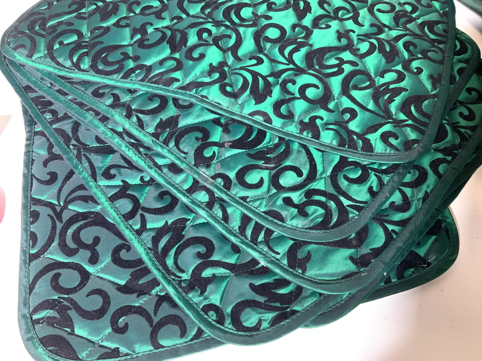 Collection of Cotton Table Napery, Placemats: 8 quilted placemats of metallic green velvet with black scrolls , 2 plissé black linen placemats, 17 black cotton dinner napkins, green cotton tablecloth 80 x 58 in. App with 4 near color teal dinner