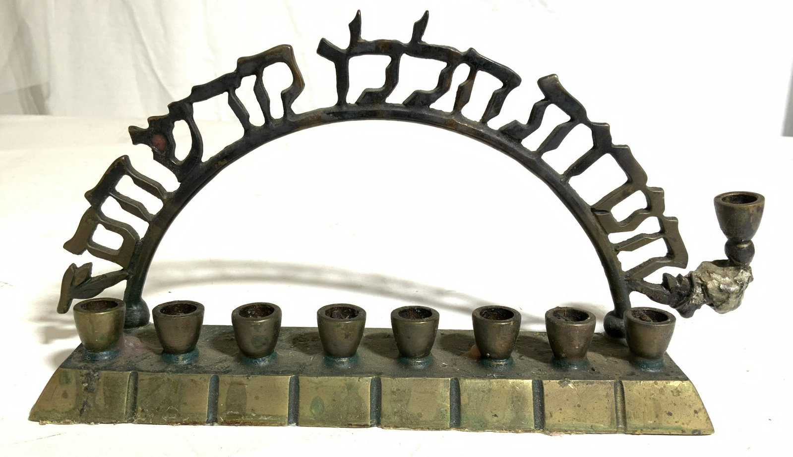 Vintage Gold Toned Brass Menorah, Judaica: Menorah is gold toned and brass. Piece has Hebrew characters in an arch shape. Underside of piece reads MADE IN ISRAEL. Piece measures approx 8 inches long 4.25 inches tall. Menorah, brass menorah, ju
