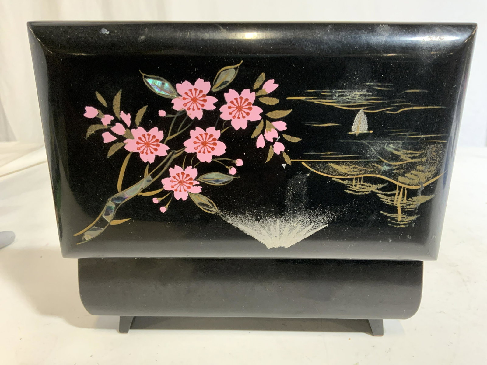 Asian Style Lacquered Trinket Music Box: Music box is black toned & lacquered. Piece has multi toned detail depicting floral, leaf, mountain, & landscape detail. Piece measures approx 6 inches long 3.5 inches deep 2.5 inches tall. Piece has 