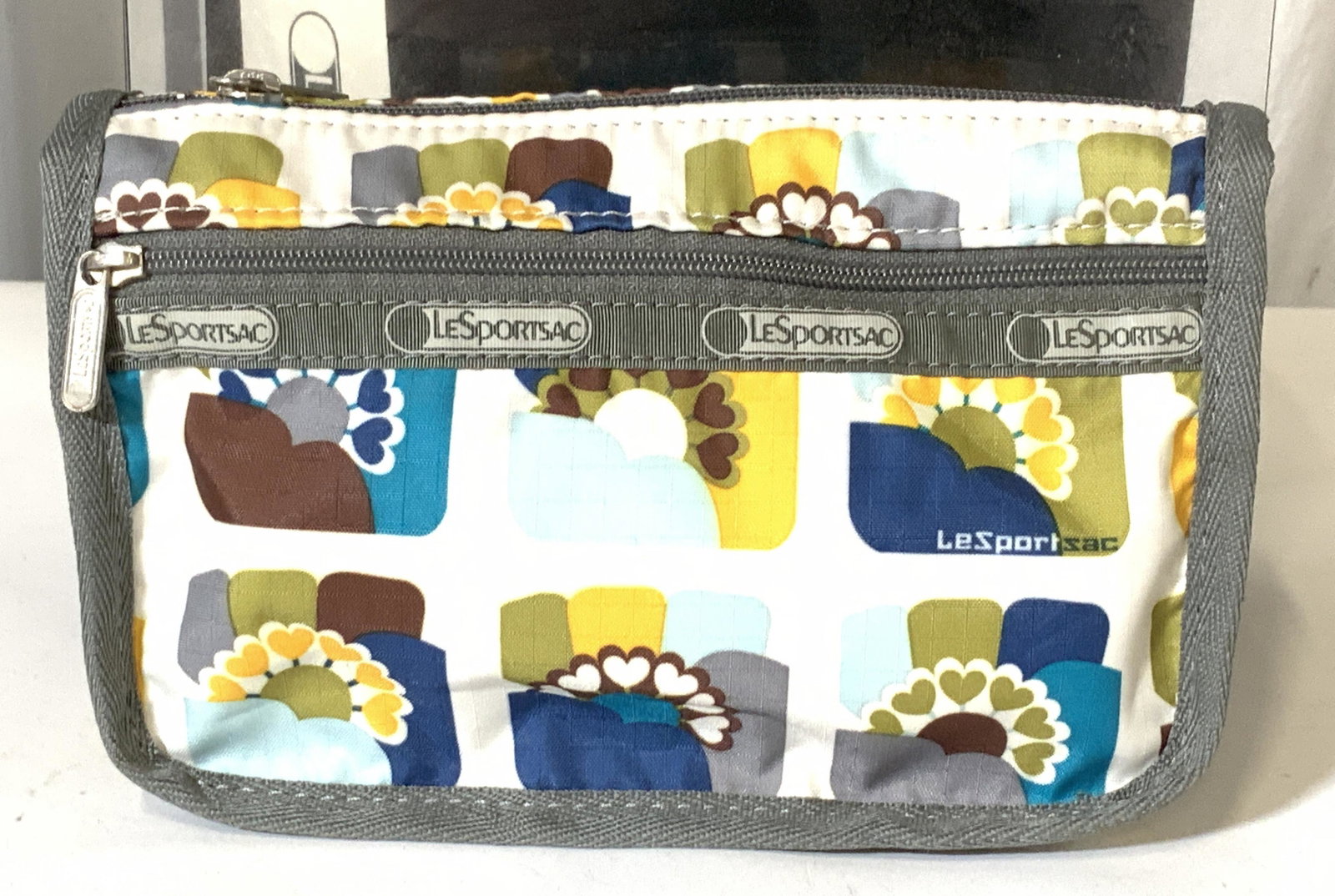 LeSportsac Never Used Org Box Cosmetic Case: Very handy travel Le Sports Sac Heart and square Pattern Cosmetic case or bag holder. Comes in original box with original tag, pattern called Aurora, measures 7.5 x 5 x 3 in. Grey chevron binding. Was