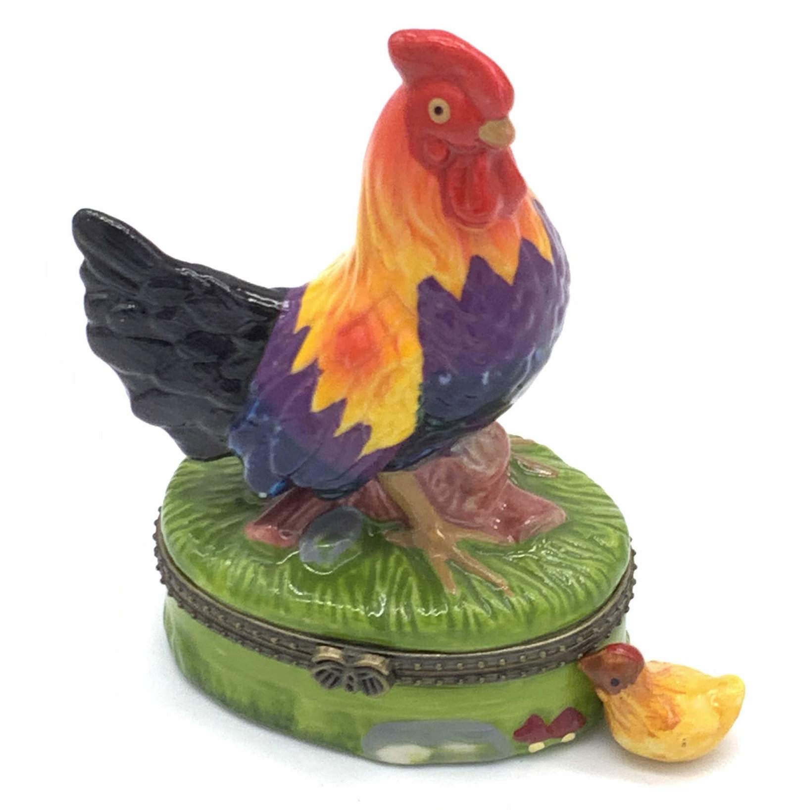 Hand Painted Porcelain Rooster Keepsake Box: A porcelain keepsake box that has been decorated with a raised rooster figurals. The exterior is a painted nature scene with raised accents. The interior of the keepsake box contains one hand painted 