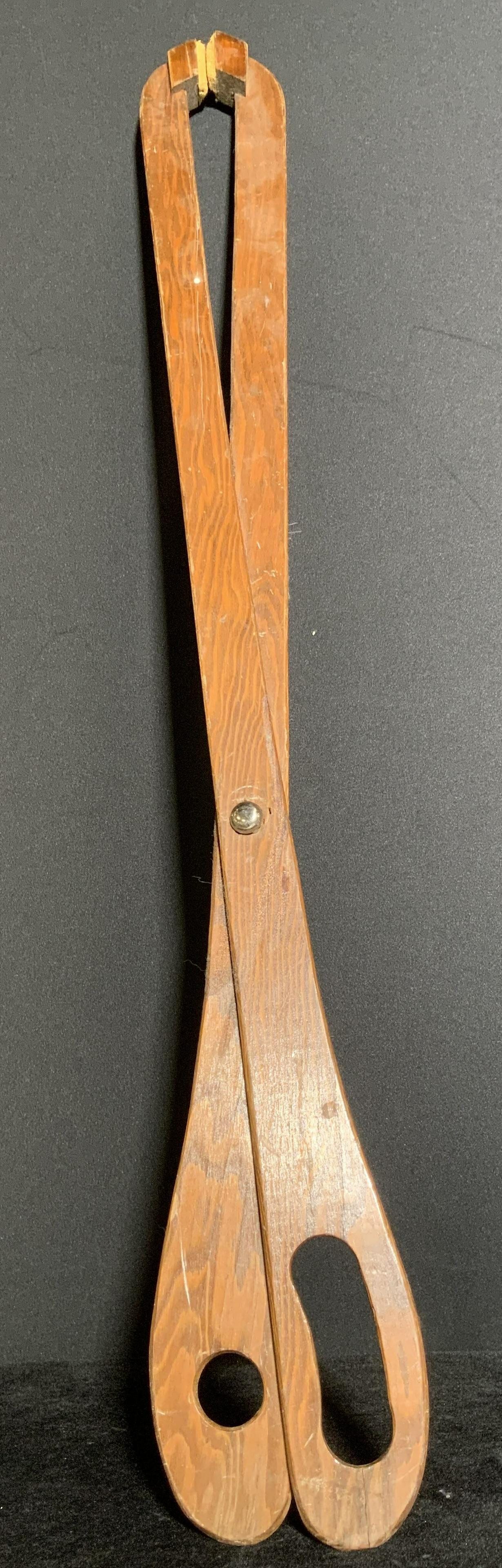 Handmade Oversized Wooden Blunted Scissors: A rich brown hued wooden pair of blunted scissors. The oversized piece measures 30L x 3W in. The piece does not open. Can be used as wall decor, tabletop decor, and more. Some wear to piece. Arts and 
