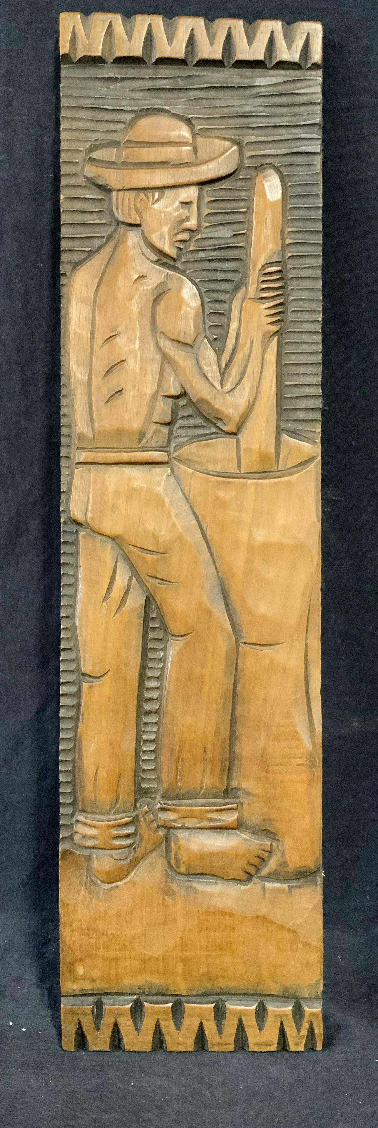 Latin American Hand Carved Wood Panel: Latin American wood panel, no apparent inscriptions or markings, subject a man holding a pole in a container possibly churning butter, appears to be hand carved, measures 25 inches tall by 6.5 inches 