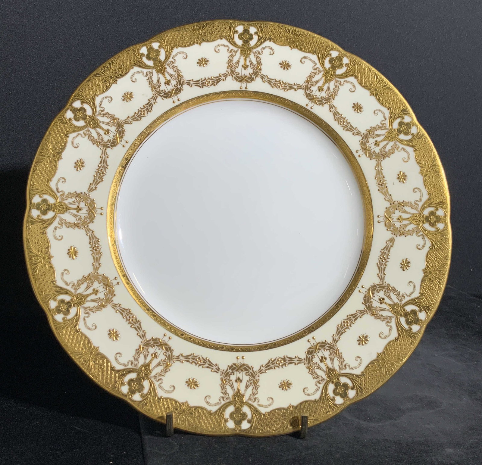 MINTON BURLEY & CO. Signed Gilt Porcelain Plate: A white porcelain plate that has gilt accents. The gilt border around the rim is slightly raised. Slightly scalloped rim. The underside is stamped MINTONS. BURLEY & CO. CHICAGO. MADE IN ENGLAND. Appro