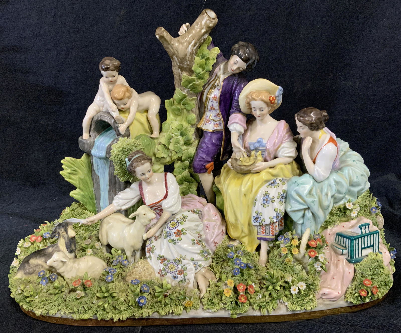 Japanese Dresden Porcelain Figural Sculpture: Japanese Dresden porcelain figural sculpture, stamps to underside illegible and faded, subject a group people with animals in a flowering field, hand painted with partially glazed surfaces, measures a