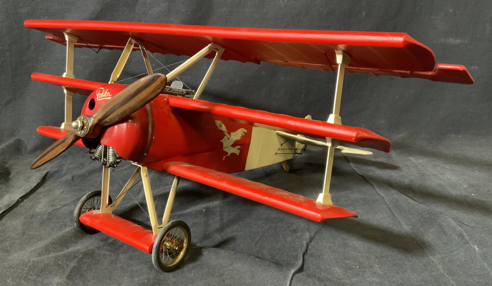 Vintage Model Triplane Fighter Plane: Vintage Model Triplane Fighter Plane, vintage possibly antique, label to underside too faded to be legible, plane colored red and white with a bird motif to the sides, propeller made of a dark wood an