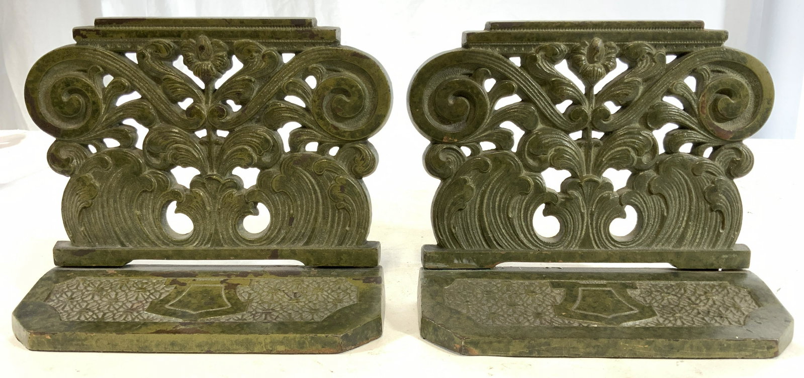 Pair Forest Green Ornate Metal Bookends: Bookends are forest green toned. Each have ornate floral & s scroll structures. Bookends appear to be iron. Underside has green toned felt on underside. Bookends are possibly vintage. Each measures ap