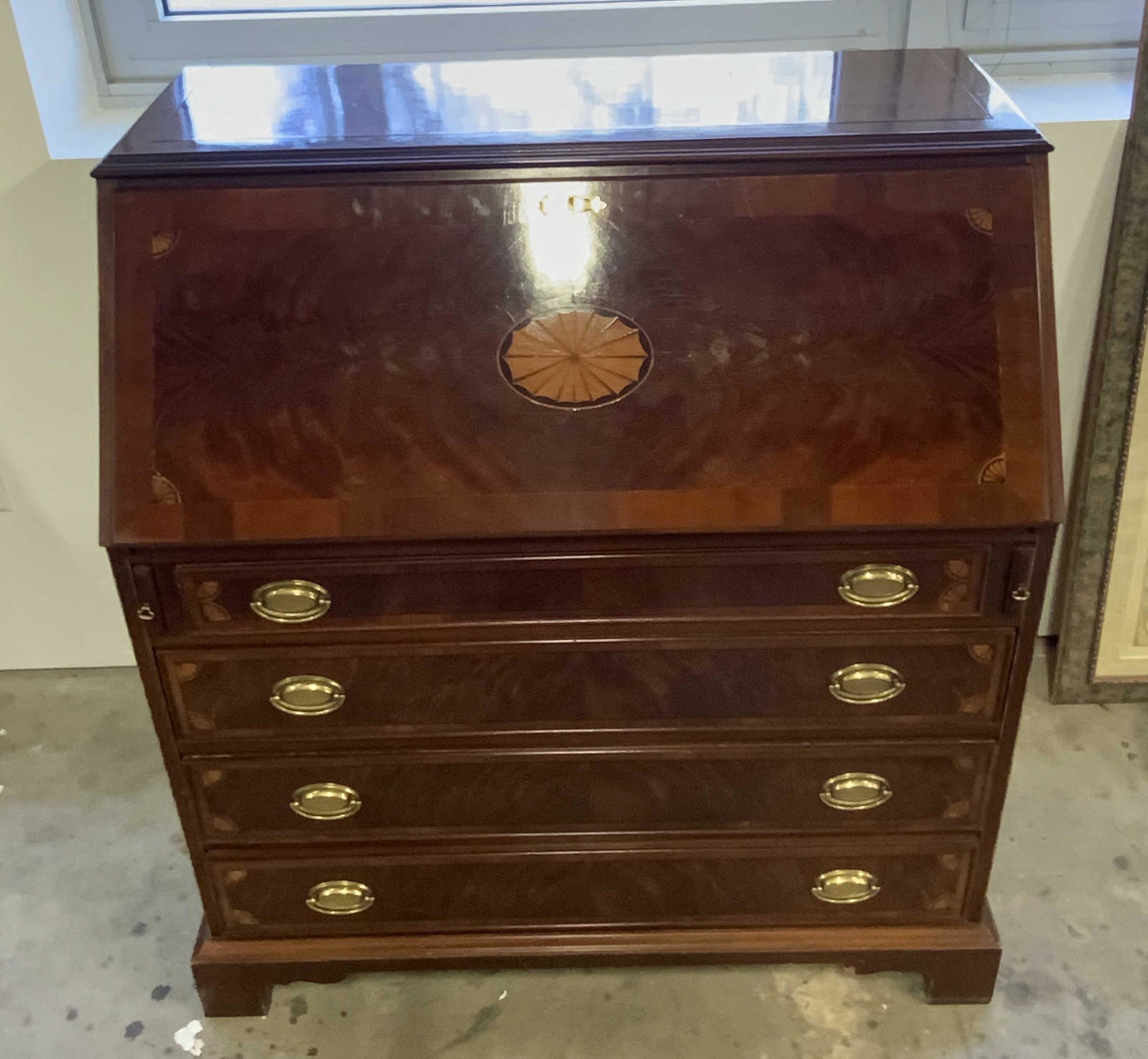 Vintage Wooden Secretary Desk W/ Leather Inlay: Vintage wooden secretary desk with a green leather inlay. The piece is crafted from deep brown hued wood and possesses brass hued metal hardware. Four drawers on exterior, six cubbies to interior, thr