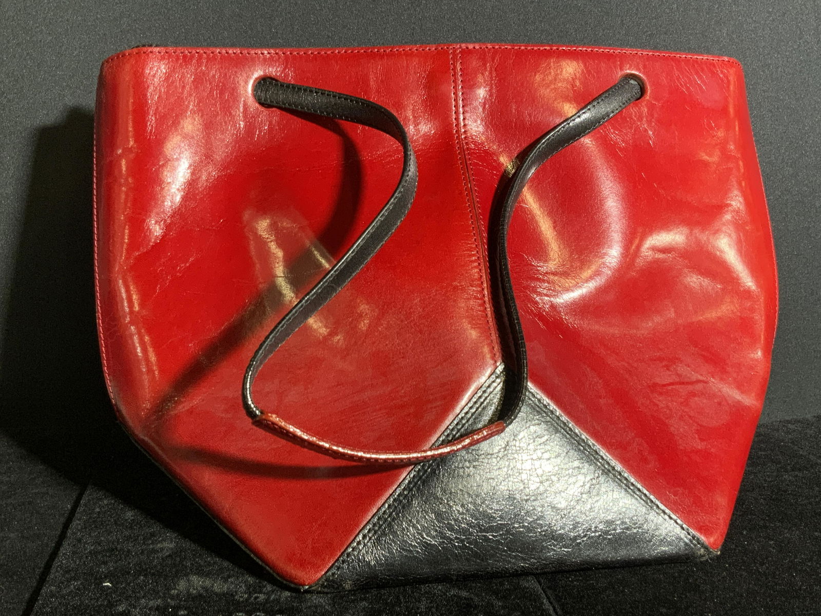 TUSK Black & Red Leather Style Ladies Purse: A red and black leather style purse with twin top handles. Snap button closure. Interior is lined with light hued fabric. Interior possesses pockets. Interior brand trademark resembles an elephant and
