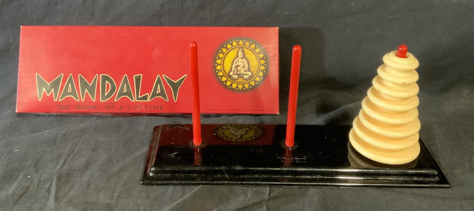 Mandalay Brain Teaser Game: Mandalay brain teaser game, comes in original packaging with board three red rods and 8 discs, instructions are written on the interior of the lid of the box, box measures 14.5 inches tall by 5 inches
