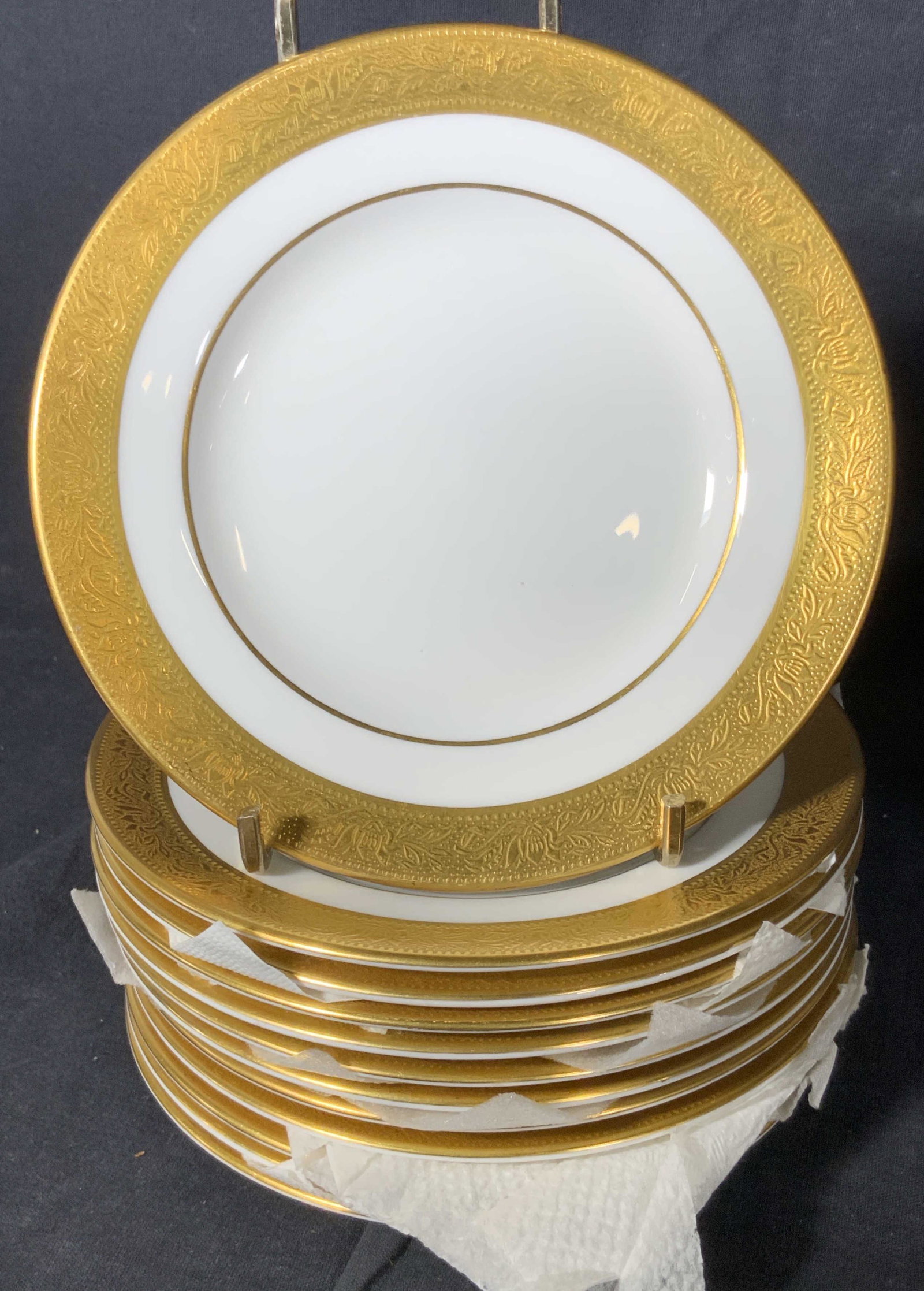 Set 76 WEDGWOOD English Bone China Dinnerware: All pieces are comprised of white porcelain with gilt line work accents along the rims. Gilt rims are slightly raised with foliage motifs. Pieces possess some wear consistent with use, discoloration a