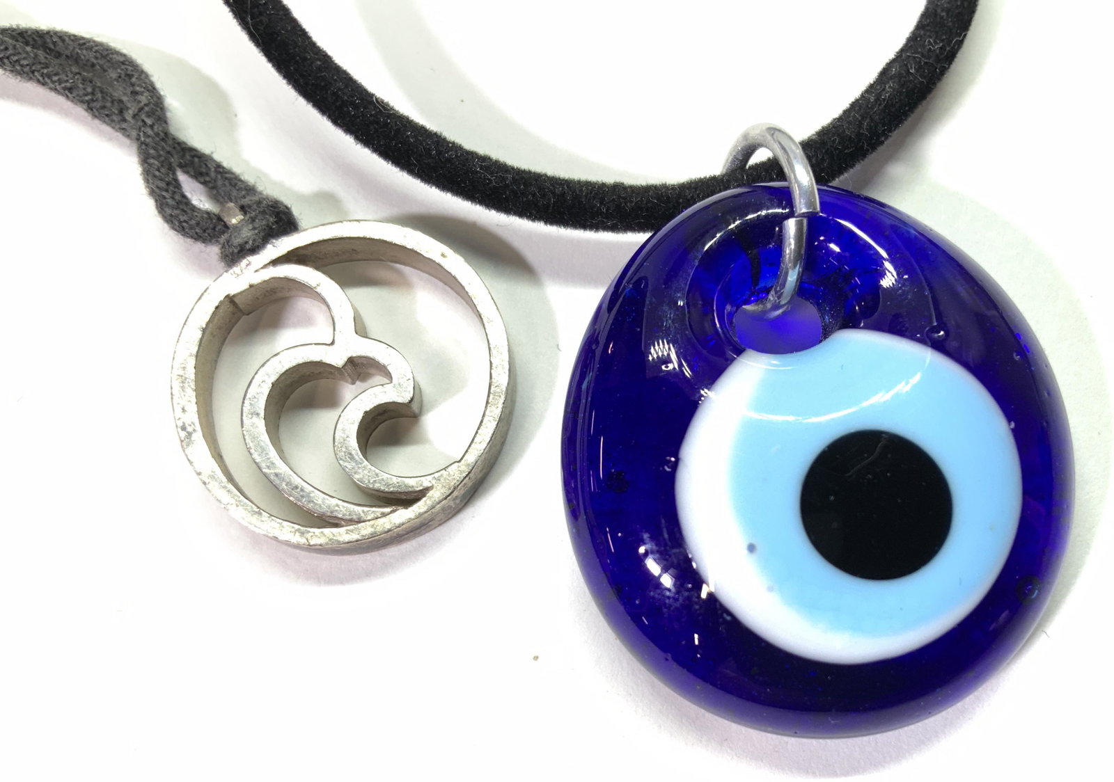 Lot 2 Fashion Boho Necklaces, Glass Evil Eye: Pendant Necklaces on black cord. One open silver toned metal pendant , 21 in. Blue Art Glass Evil Eye Pendent, thick glass , 1.25 in. Plush cord 16.in. Property of New Canaan, CT Estate Pendant Neckla