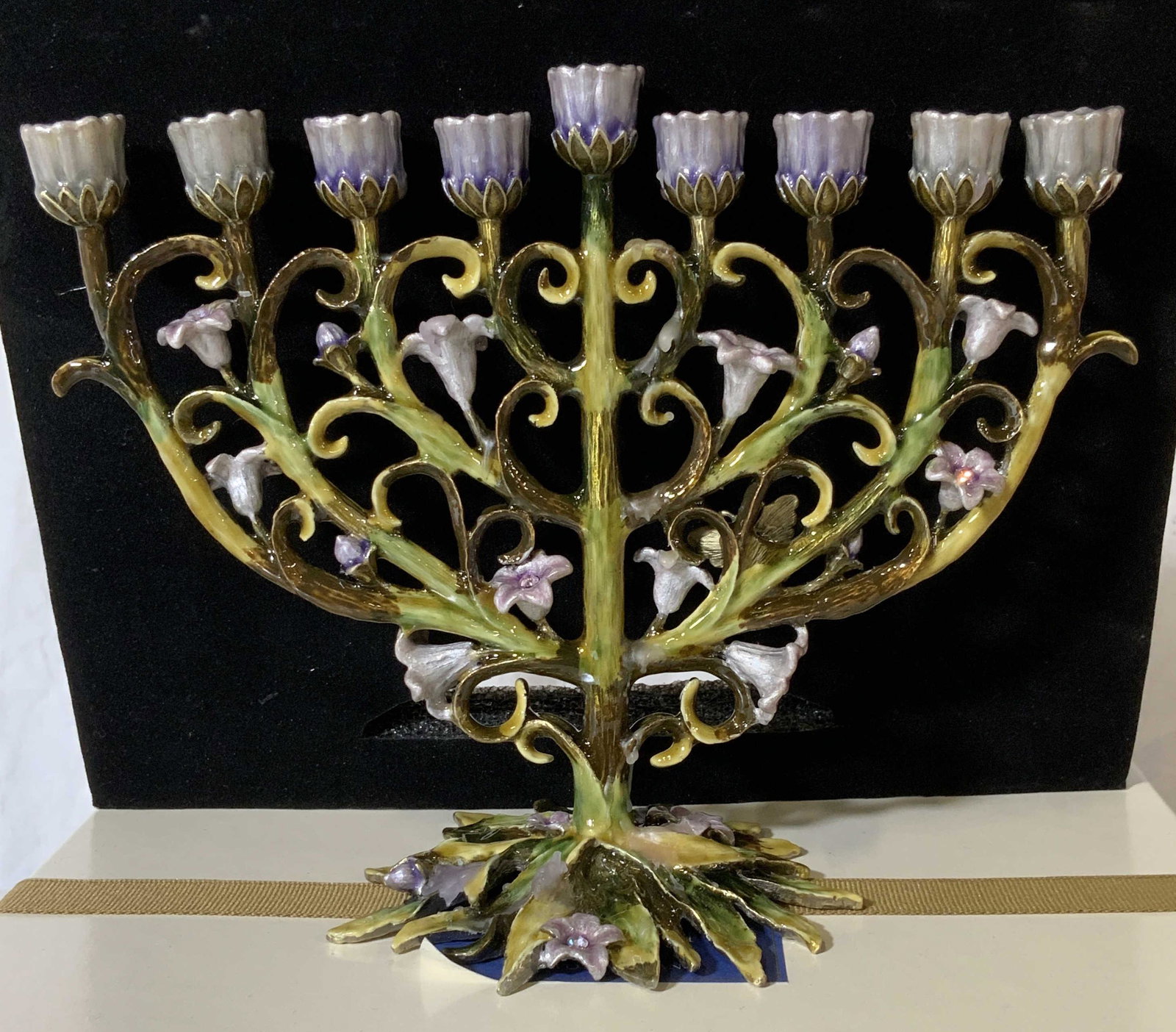Enamel & Austrian Crystal Menorah, Org Box: Two’s Company Enamel Floral Menorah with Austrian Crystals , comes in original box with foam padding, green and violet color palate , measures 8 in wide, 6.25 in ht. Jewish ceremonial, enamel menora