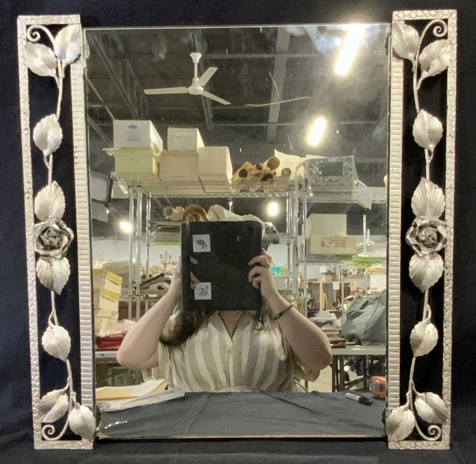 Silver Painted Floral Metal Mirror: Silver painted floral metal mirror, mirror is a vertical rectangle with framing to either side and bare mirror glass to the top and bottom, metal framing designed to look like roses and vines, measure