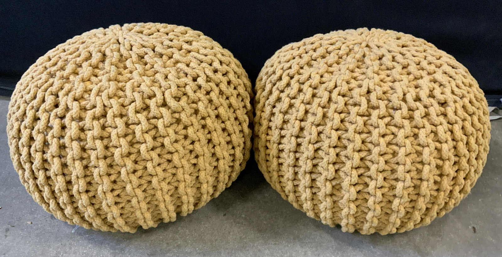 Pair Knit Braided Poufs: Pair of poufs, orange toned, fabric is braided and arranged in a chain link pattern. Wear is consistent with age and use. Each measures approx 12 inches H and 18 inches W. Property of Park Avenue, Man