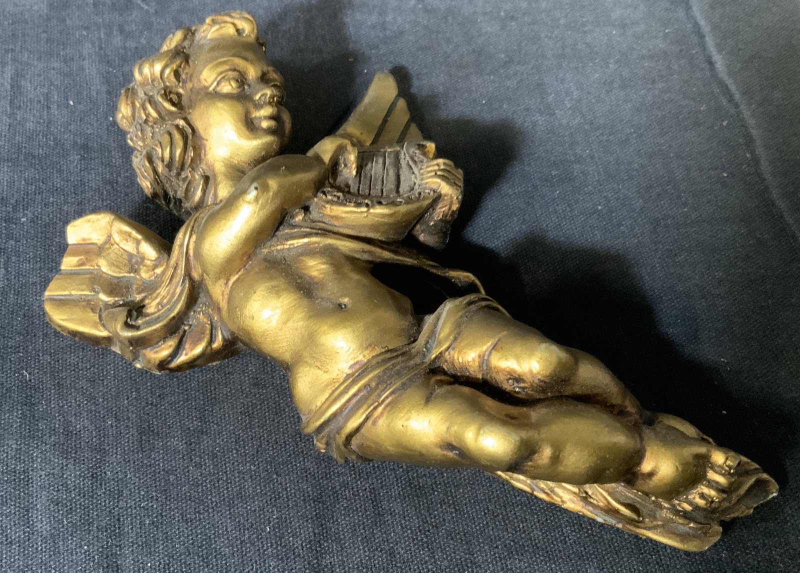 Composite Cupid Wall Ornament: Composite Cupid wall ornament, no apparent inscriptions or markings, subject a Cupid or putti playing a harp, part of wing is broken off, measures 5 inches at tallest point, hole to halo of Cupid for 