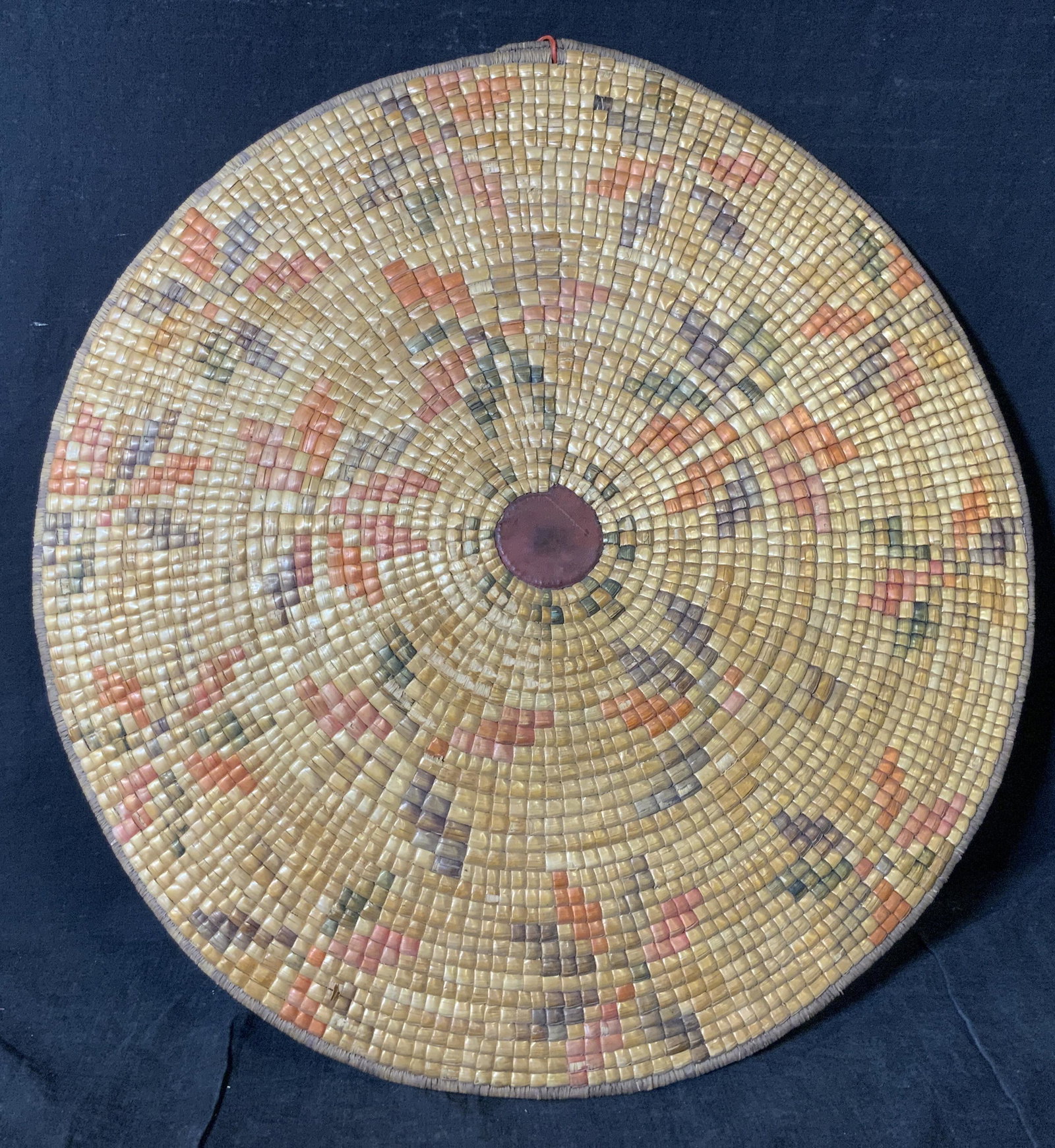 Hand Crafted Wicker Wall Ornament: Hand Crafted wicker wall ornament, piece woven around a leather bound focal point to the center, exterior of piece has variously colored section of wicker, flip side of piece has a single tone with so
